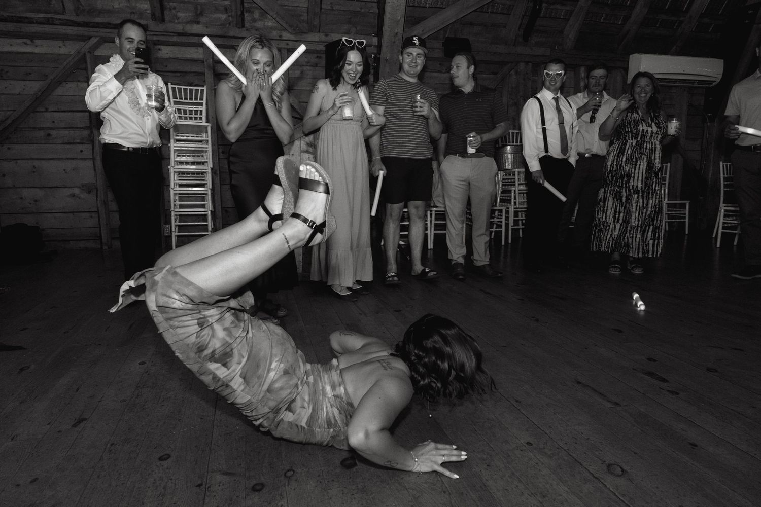 Wedding guests dance and celebrate on a dark dance floor during a reception party.