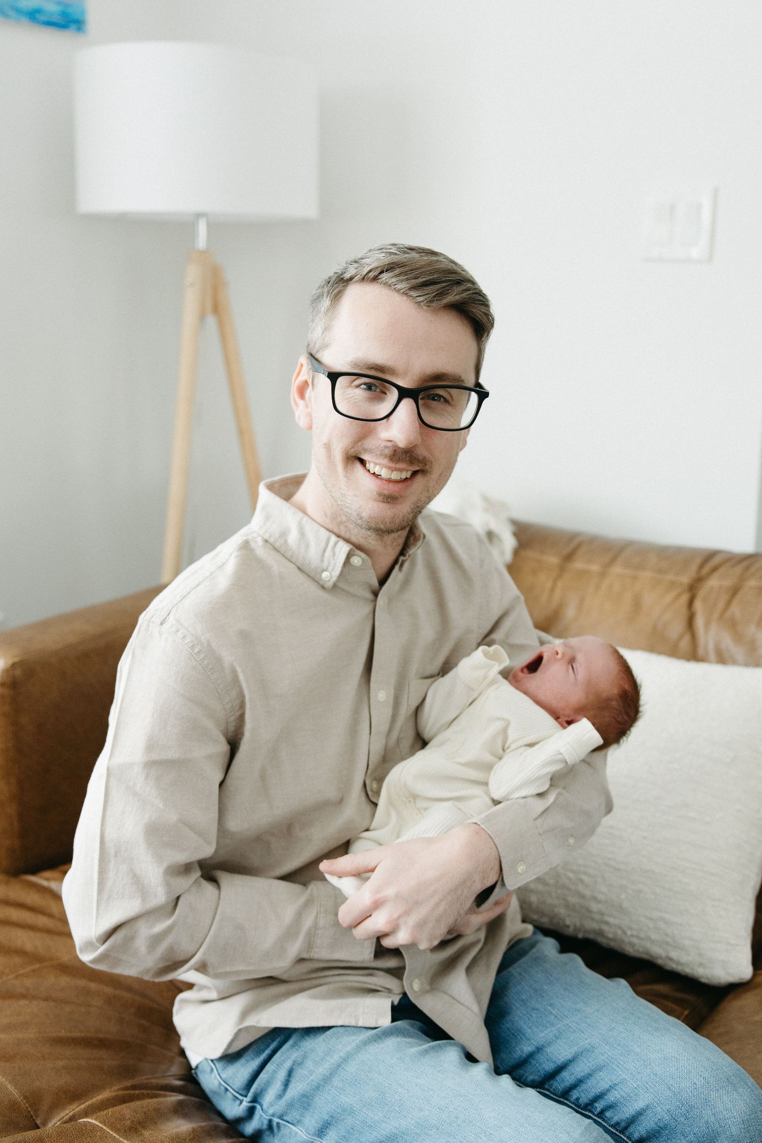 Series of candid shots showing tender moments between parent and newborn on a brown couch.