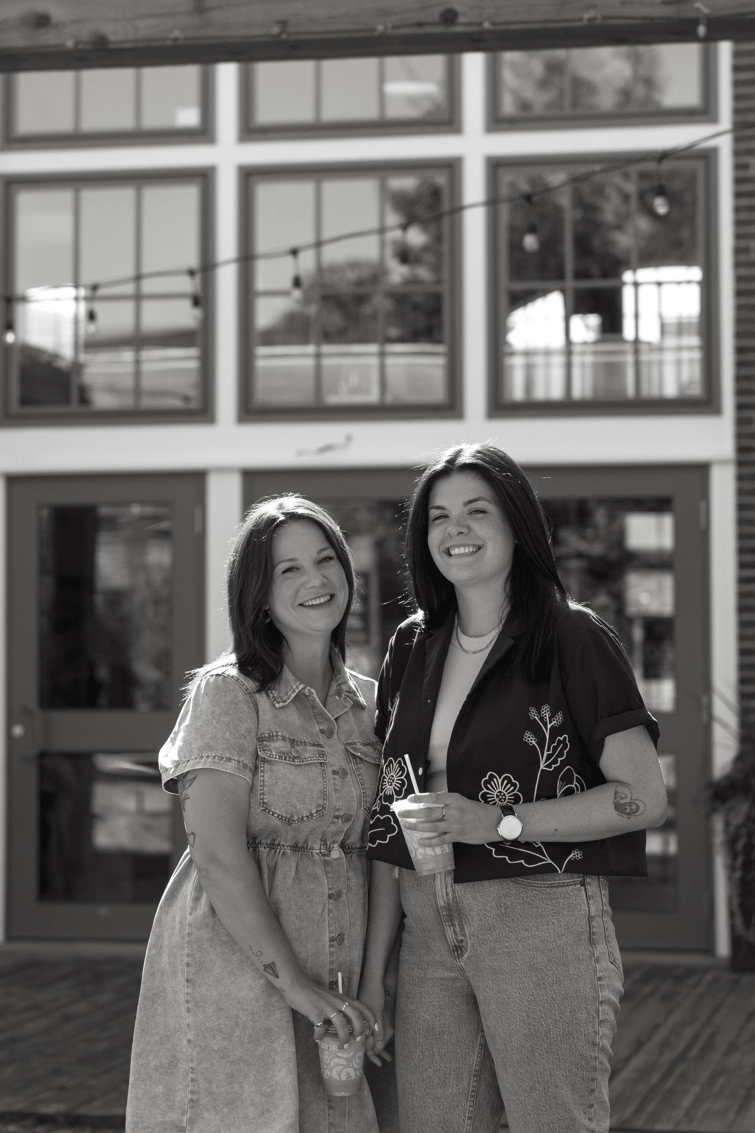 Two friends sharing a joyful moment outside a building with glass windows.
