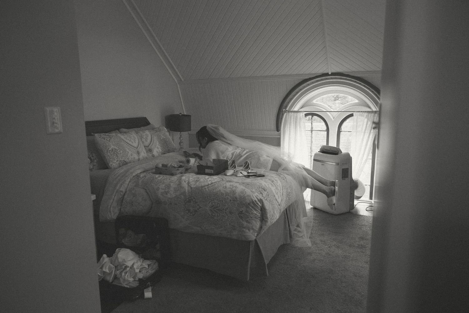 Sunlit bedroom interior with white bedding and arched windows.