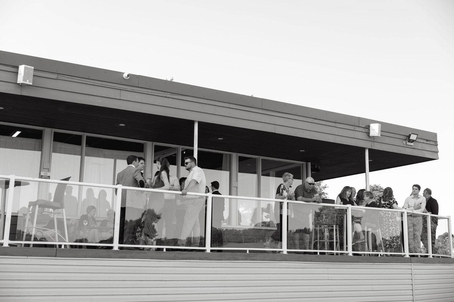 Modern architectural venue with guests viewing from a glass-enclosed balcony area.