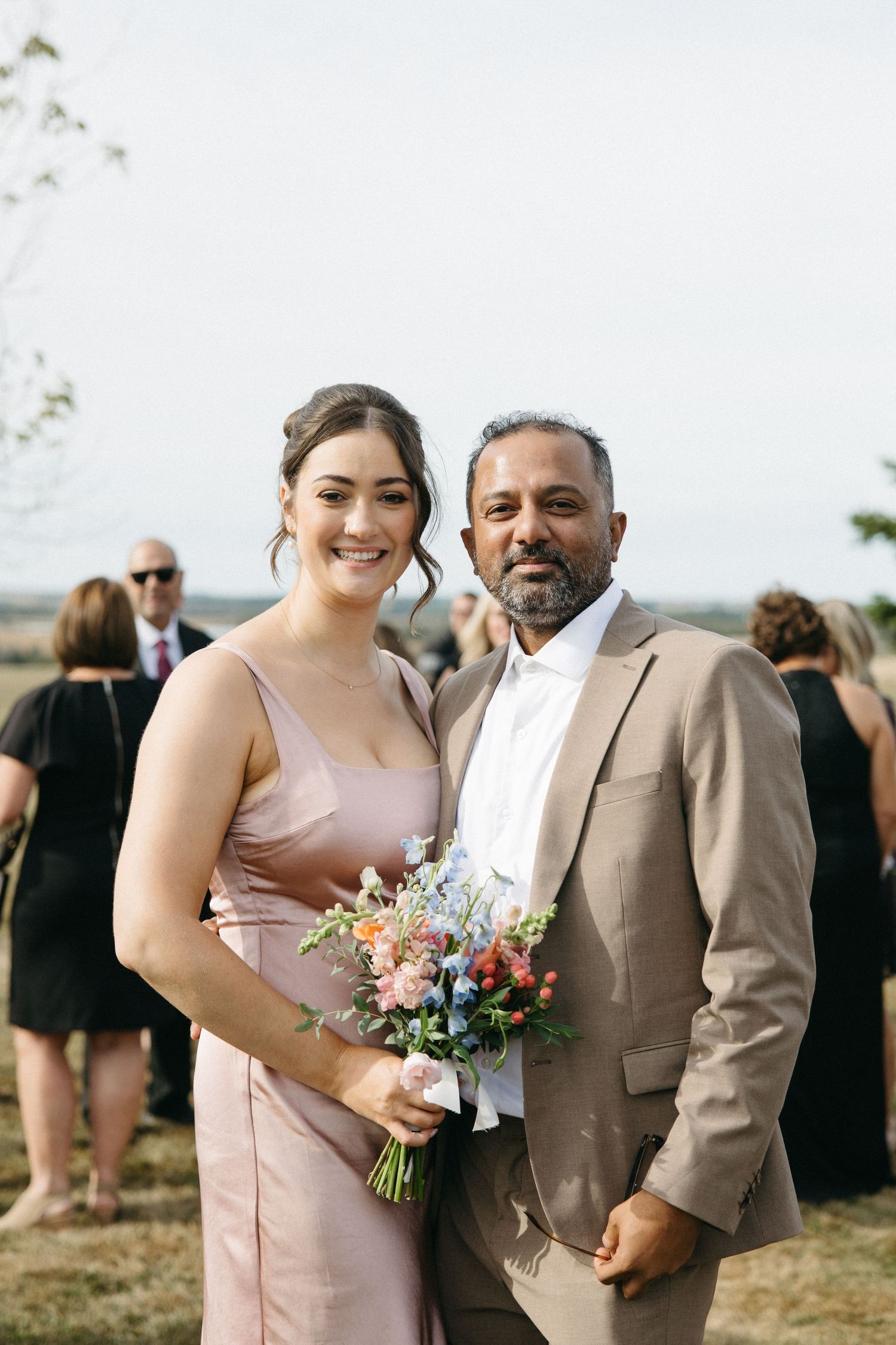 Wedding couple poses with colorful bouquet outdoors.