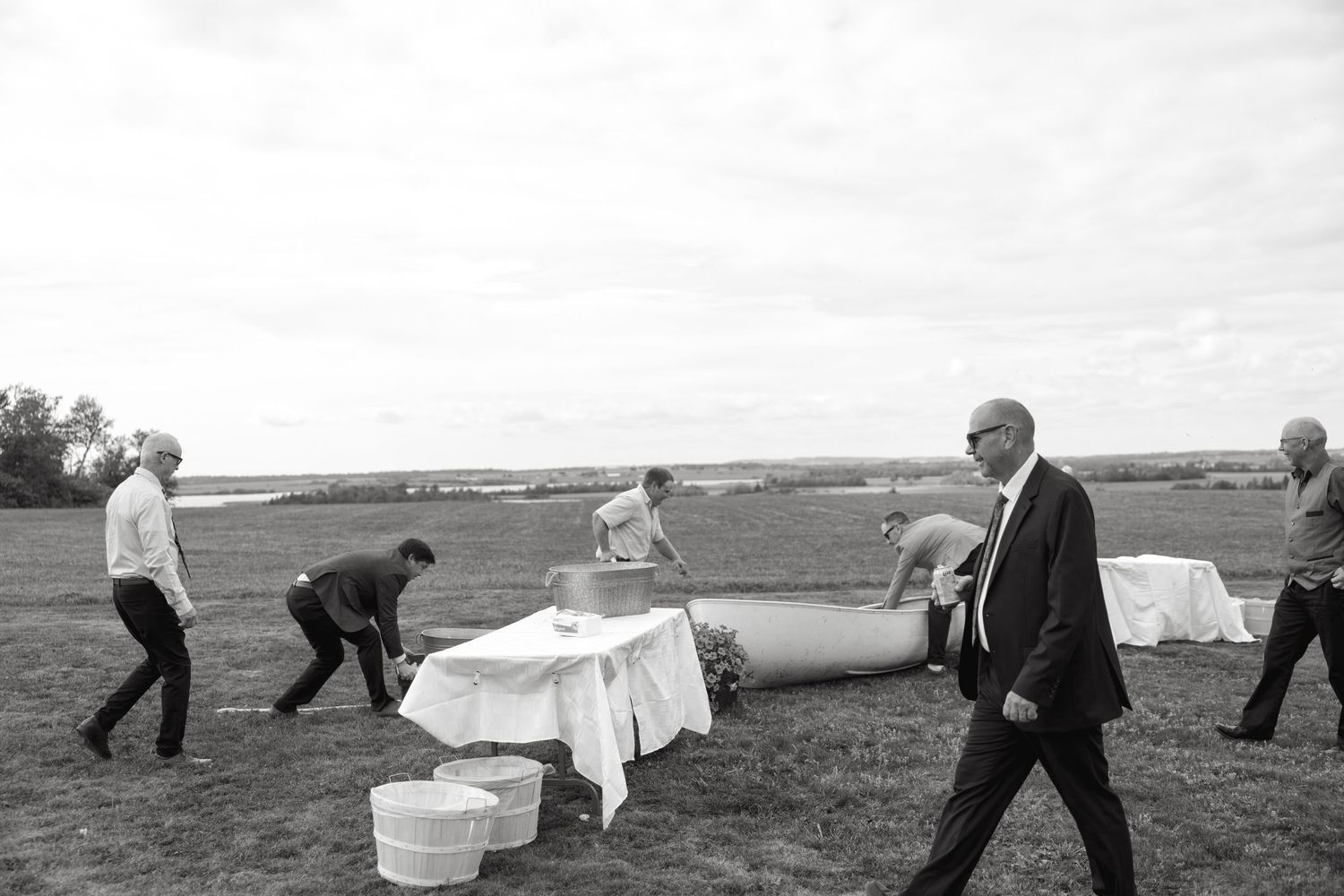 People working together to set up white fabric decorations outdoors on a cloudy day.