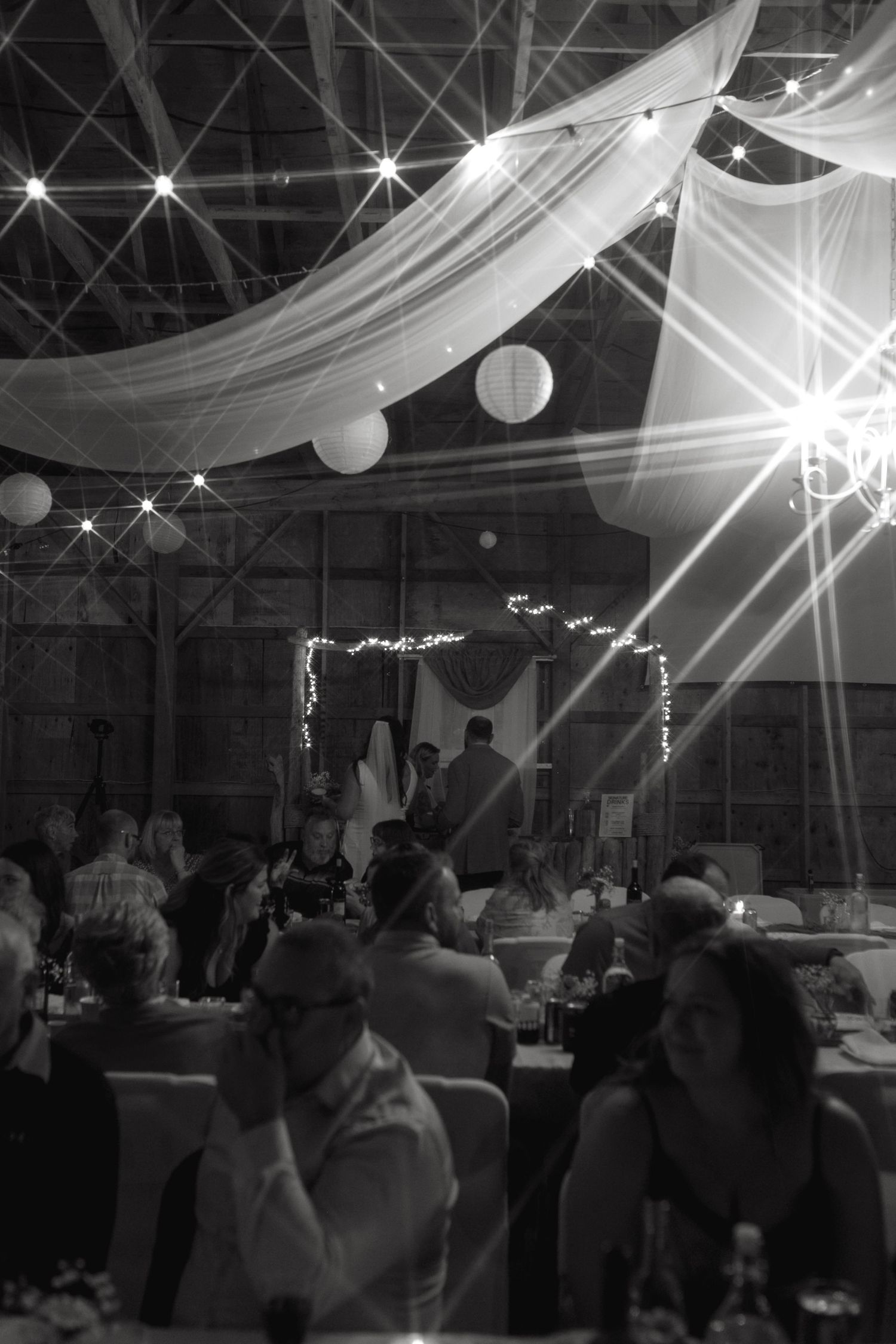 Indoor wedding reception venue with dramatic lighting and draped fabric ceiling decorations.