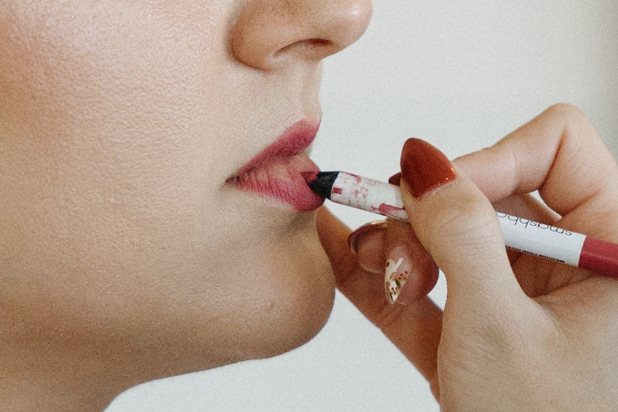 Close-up shot of applying red lipstick with a brush.