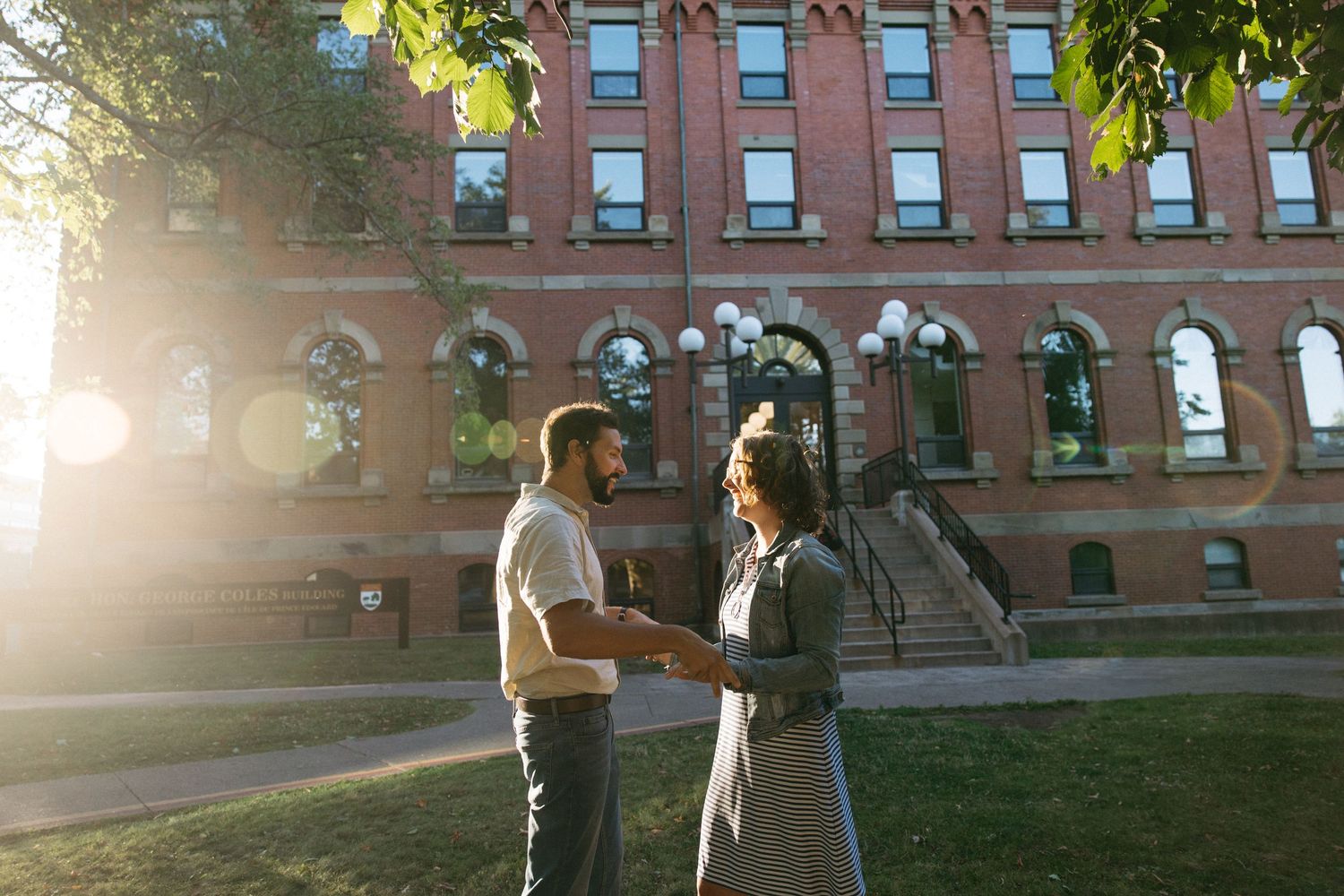 A couple shares tender moments outside a historic brick building at sunset.