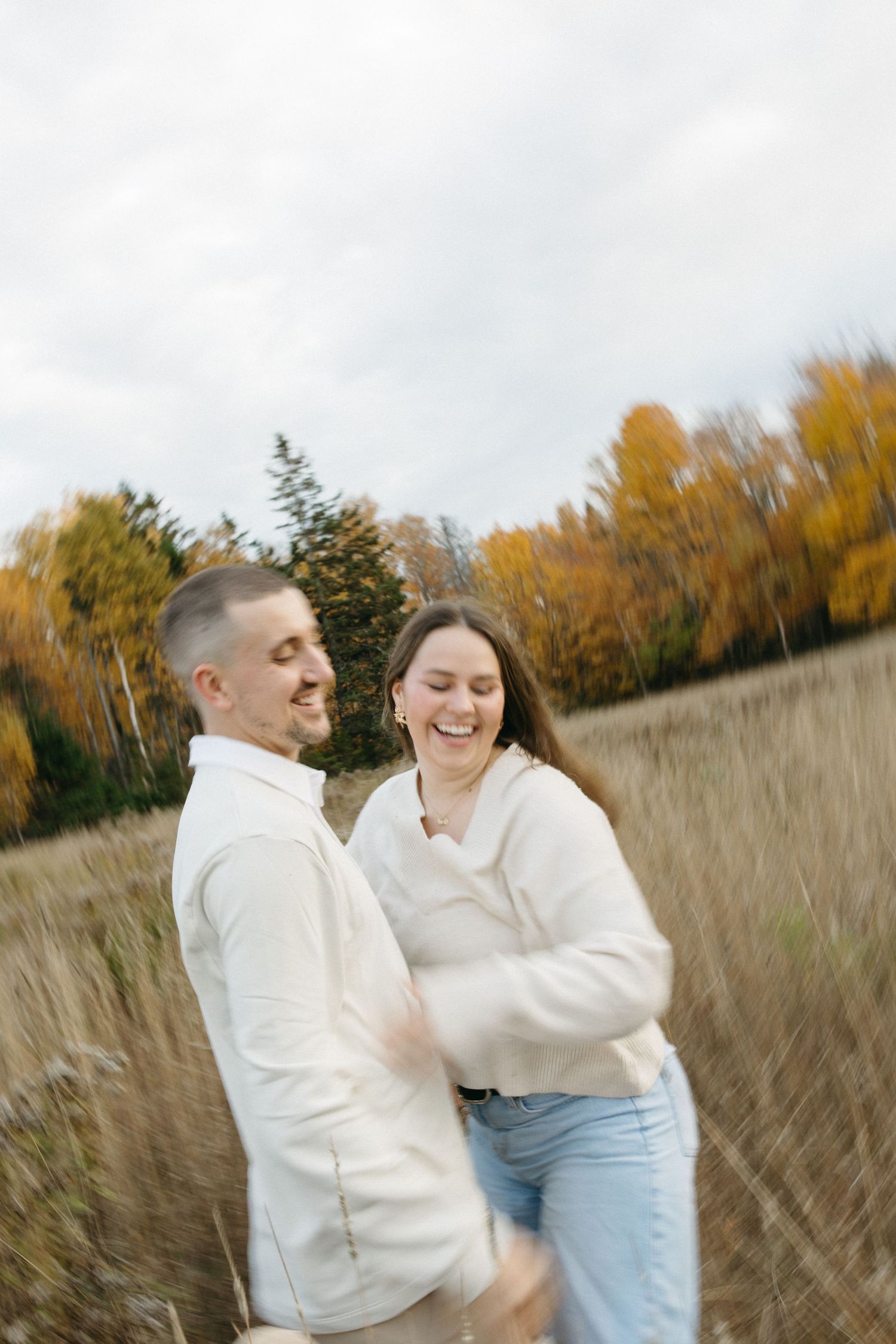 Playful moment captured in a field with golden fall foliage behind.