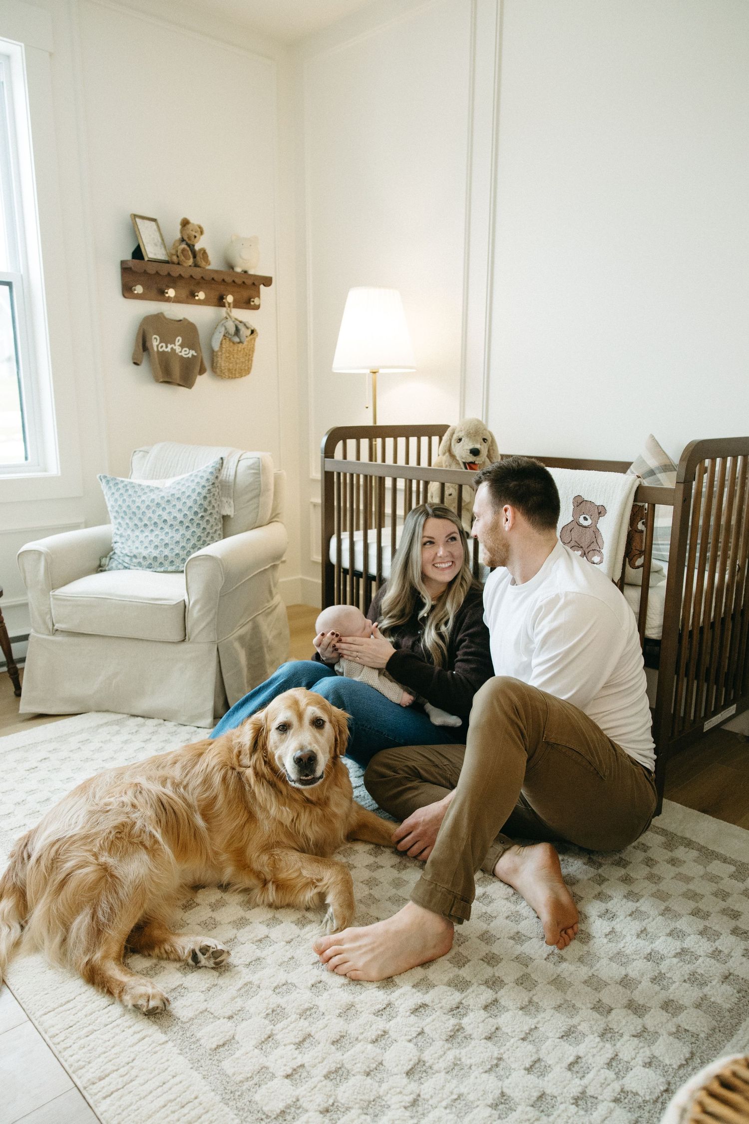 Casual family moment in nursery with golden retriever on geometric rug.