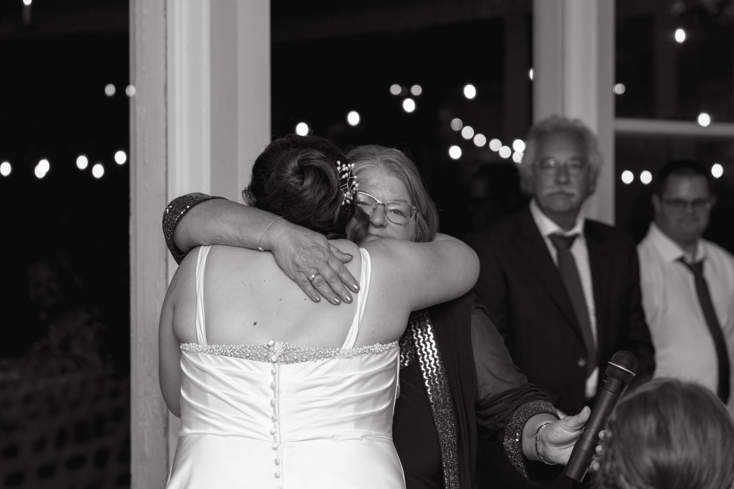 Black and white photo of bride embracing guest at wedding reception.