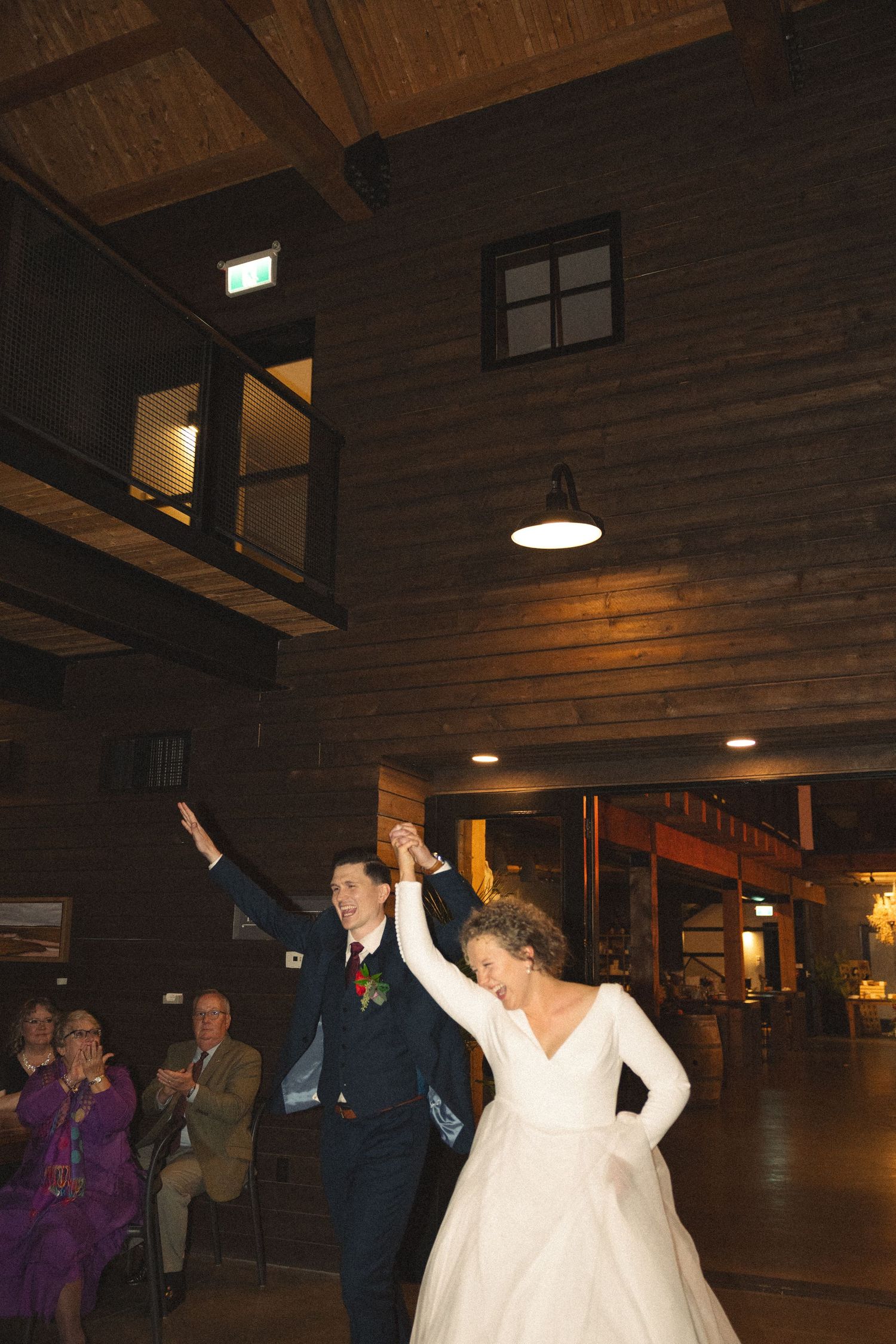 Guests dance and celebrate on a wooden dance floor at an indoor wedding reception.