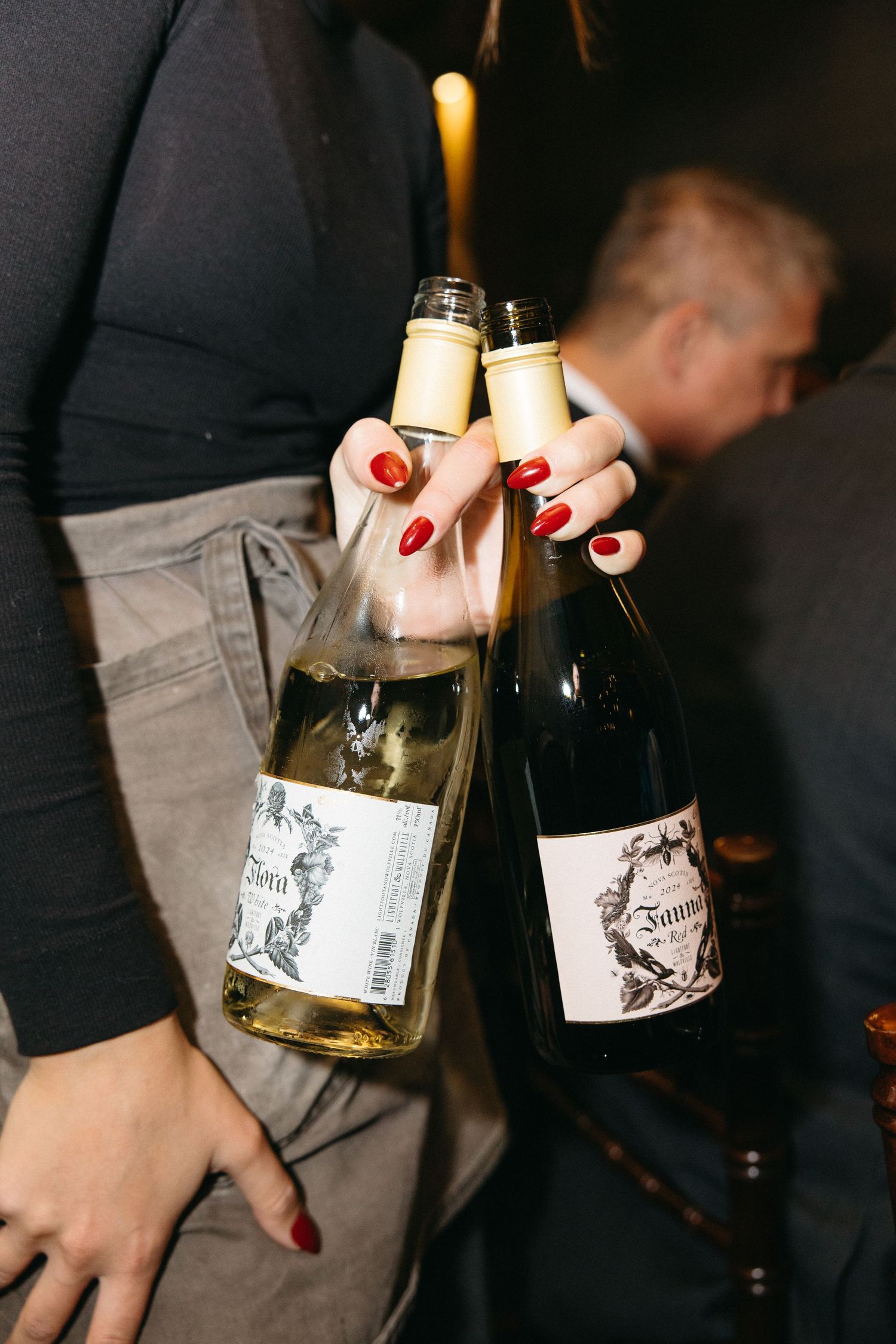 Hands holding wine bottles with distinctive black and white labels.