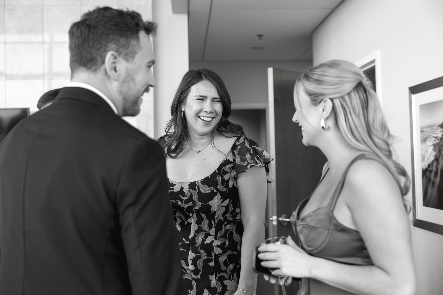 Wedding guests share laughter and conversation during a candid reception moment.