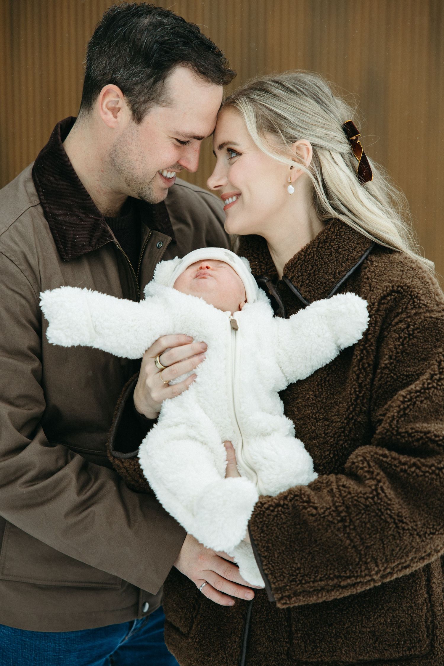 A heartwarming family moment with a baby in a plush white snowsuit.