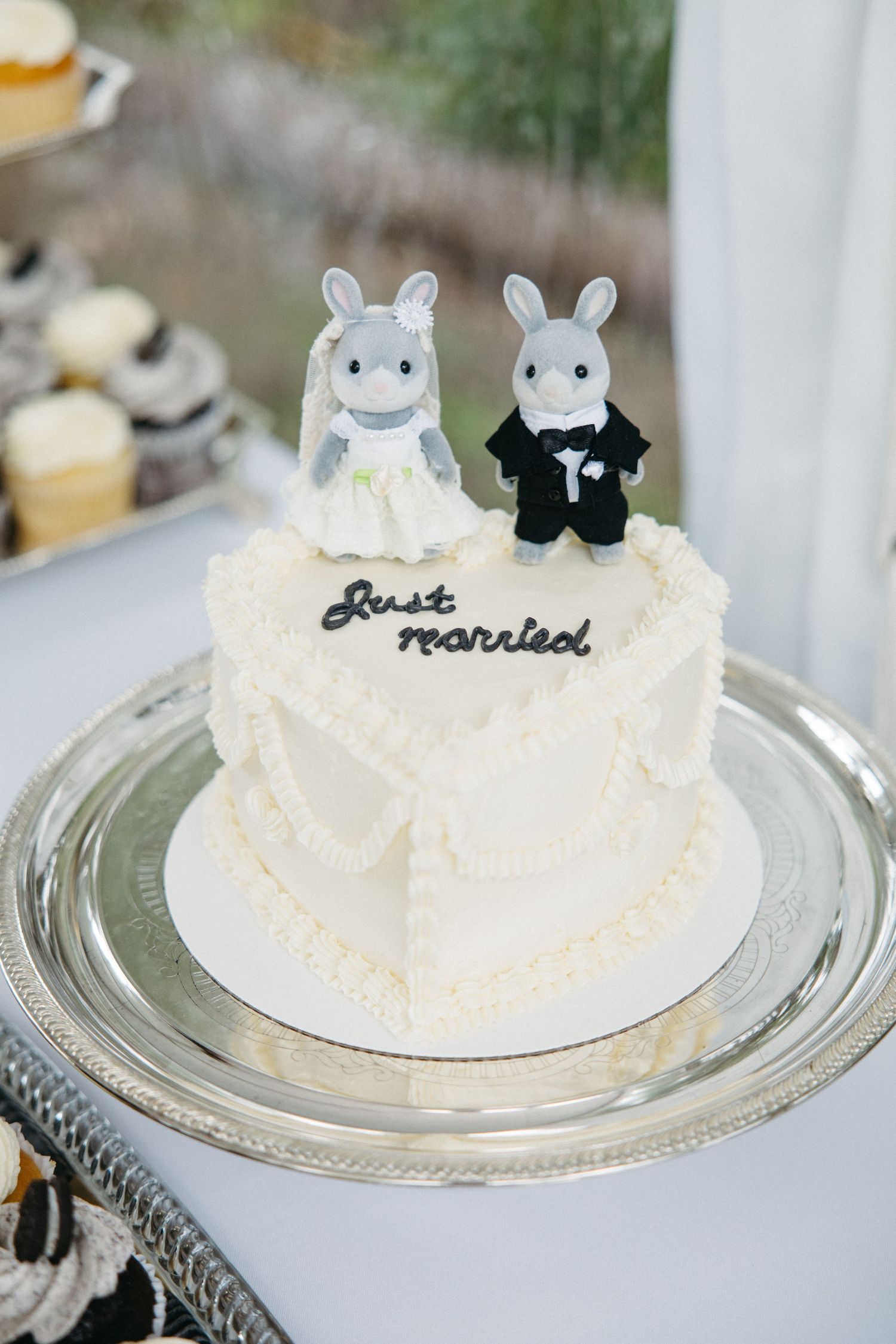 White heart-shaped wedding cake with bunny bride and groom toppers reading Just Married.