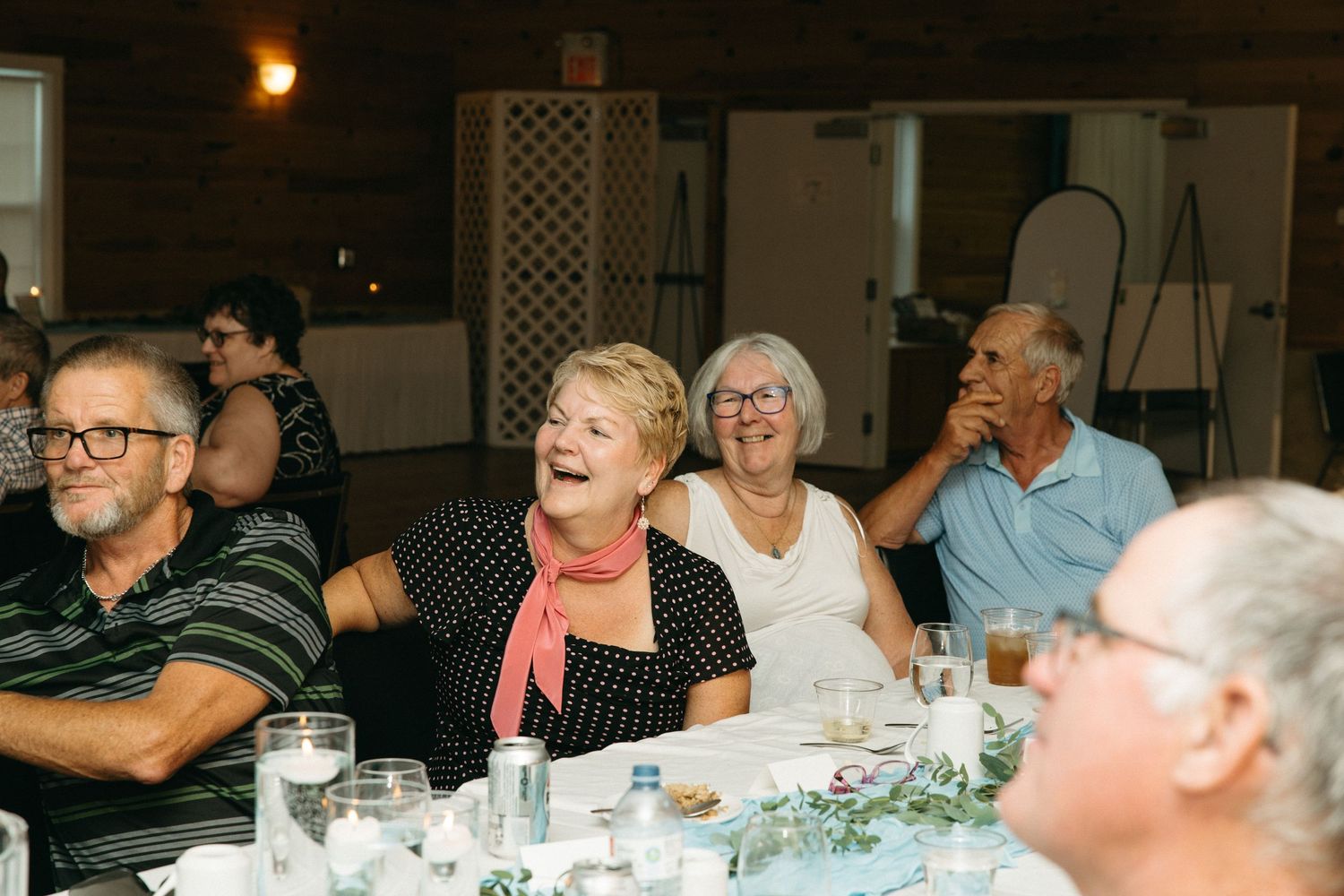 Wedding reception guests laughing and enjoying themselves at decorated dining tables.