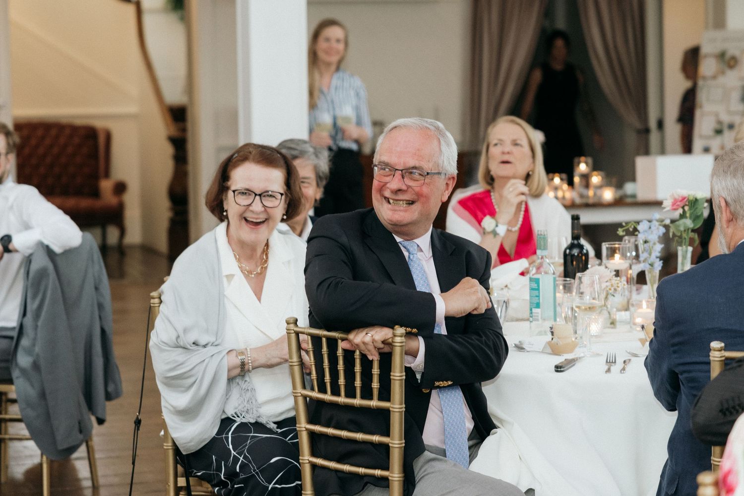 Wedding reception guests seated at elegant tables with decor and floral centerpieces.
