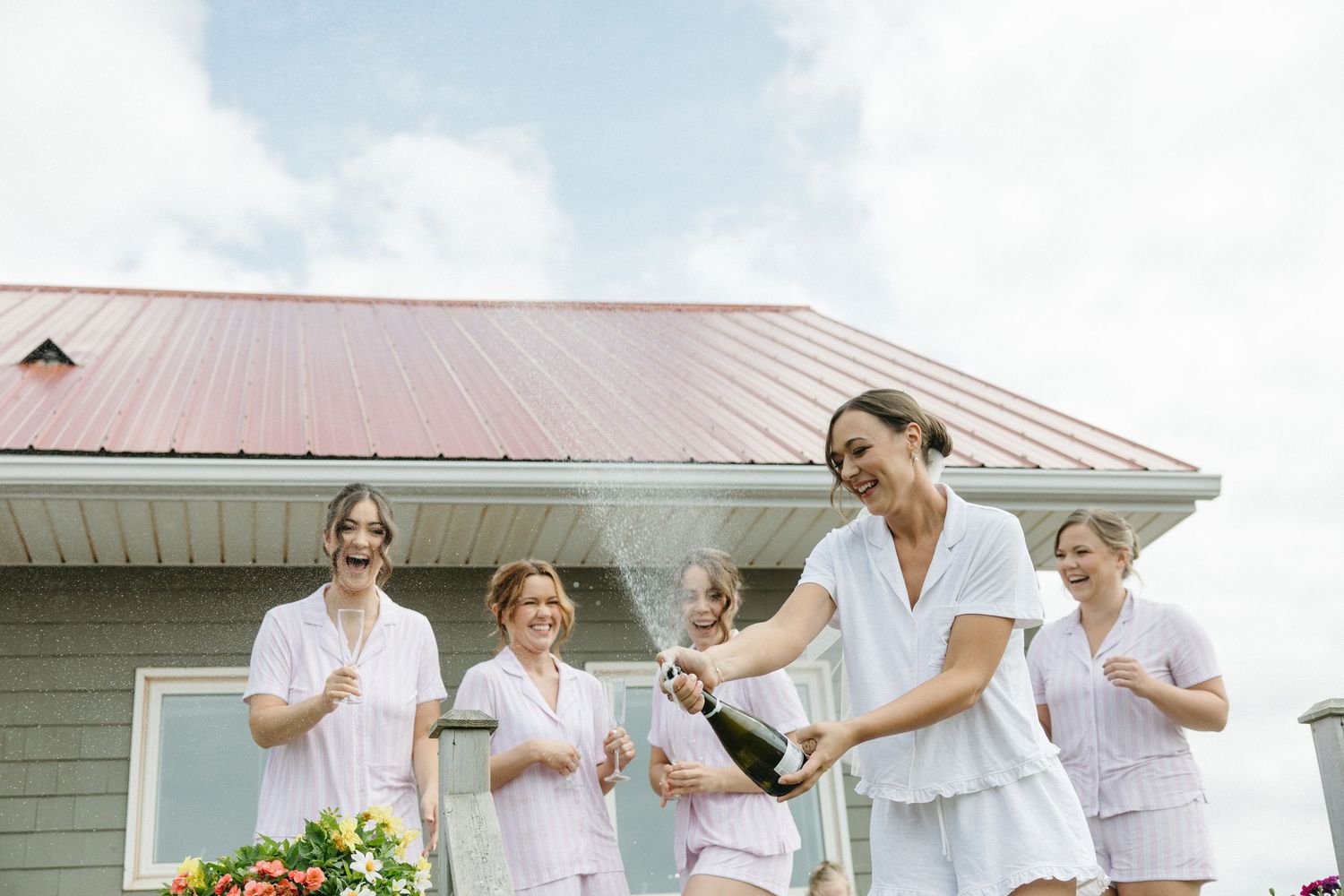 Wedding party members in light colored attire celebrating outdoors.