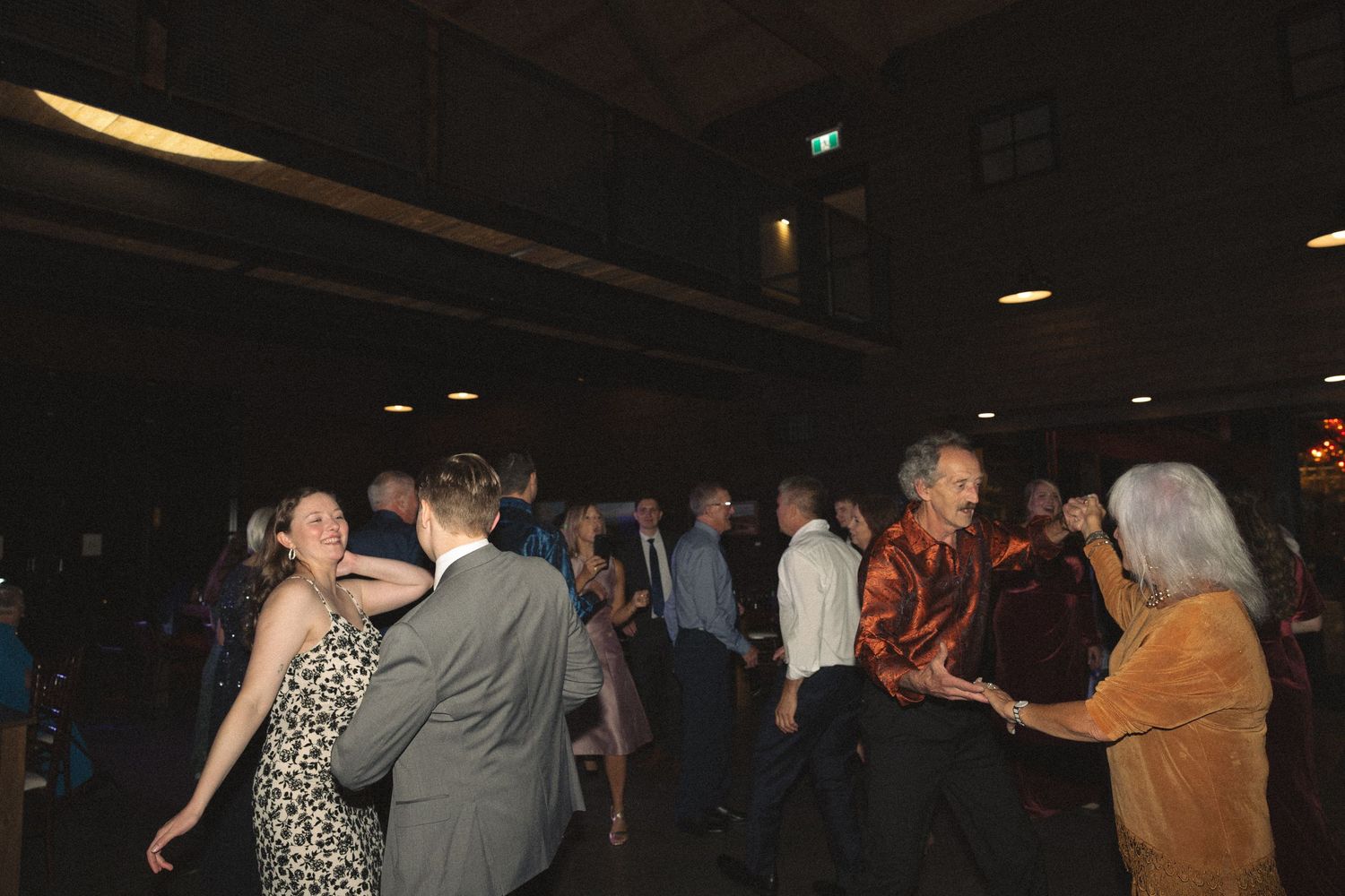 Dark reception hall with silhouettes of people dancing in the background.