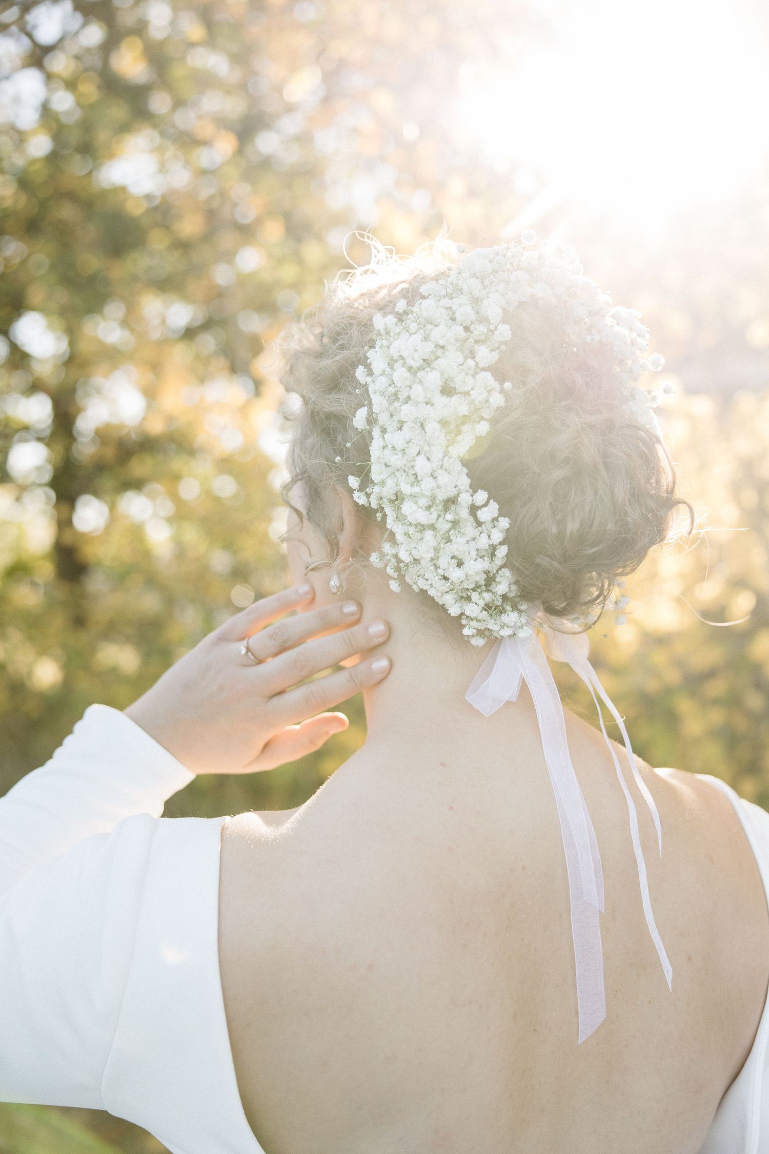 Sunlit portrait showing delicate baby's breath flowers and ribbons in bridal hair.