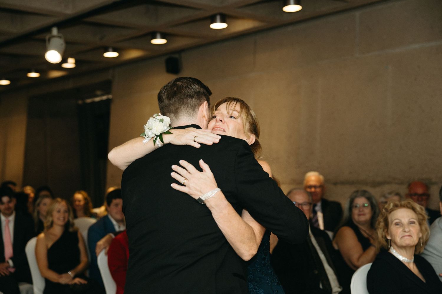 Intimate dance moment captured during formal celebration with guests in background.