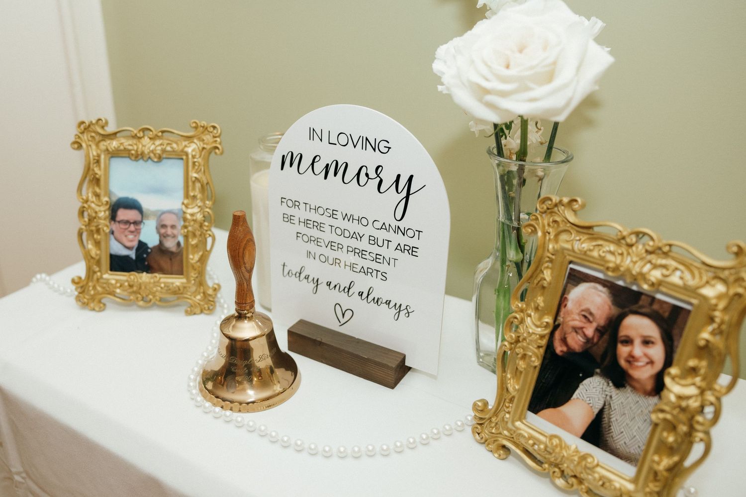Wedding memorial table with gold frames, photos of loved ones, and In Loving Memory sign.