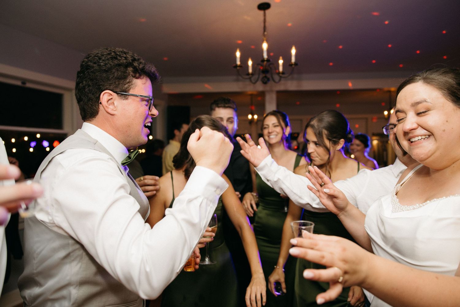 Groom dancing and celebrating with guests on a lively wedding reception dance floor.