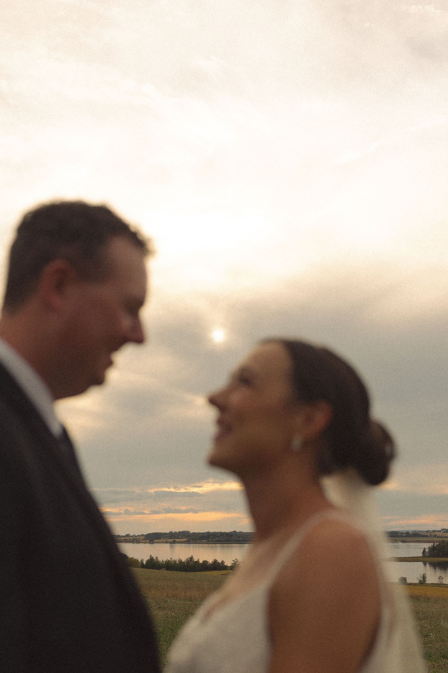 Romantic sunset portrait of newlyweds against a waterfront backdrop.