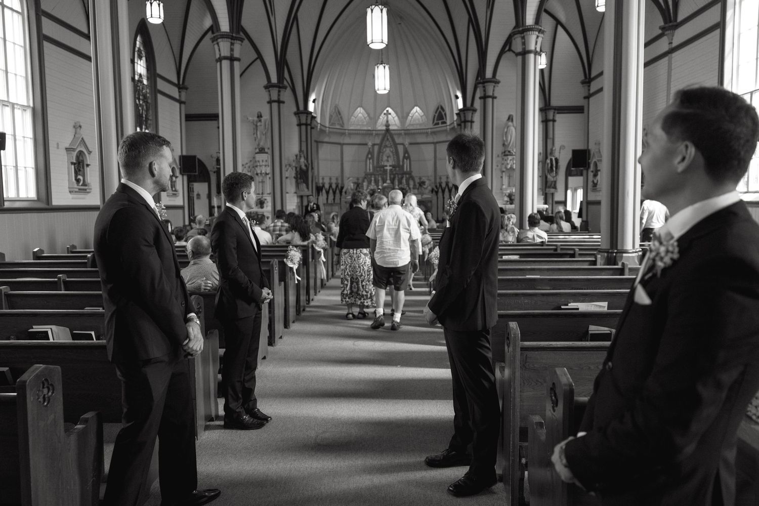Interior of a church with Gothic arches and pendant lights during a ceremony.