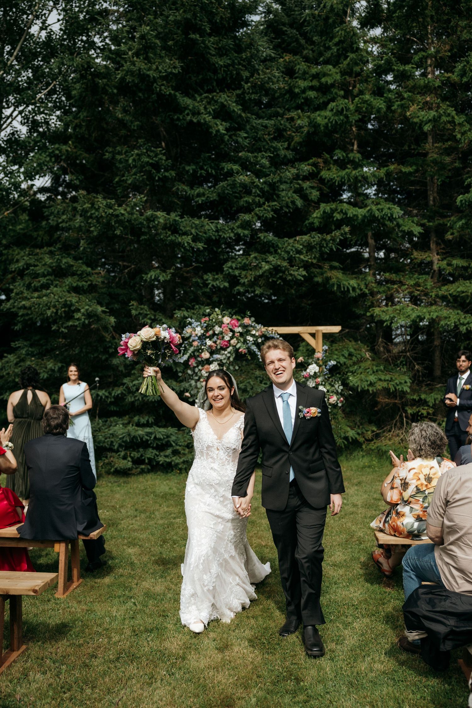 Wedding celebration sequence showing couple walking down aisle while guests seated on wooden benches cheer.