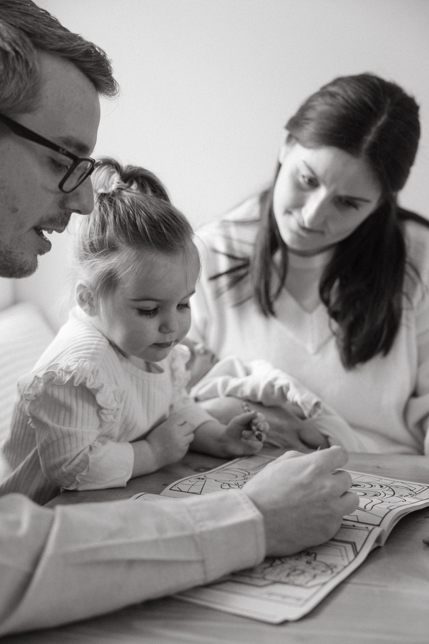 Black and white image of family members coloring and drawing together at a table.