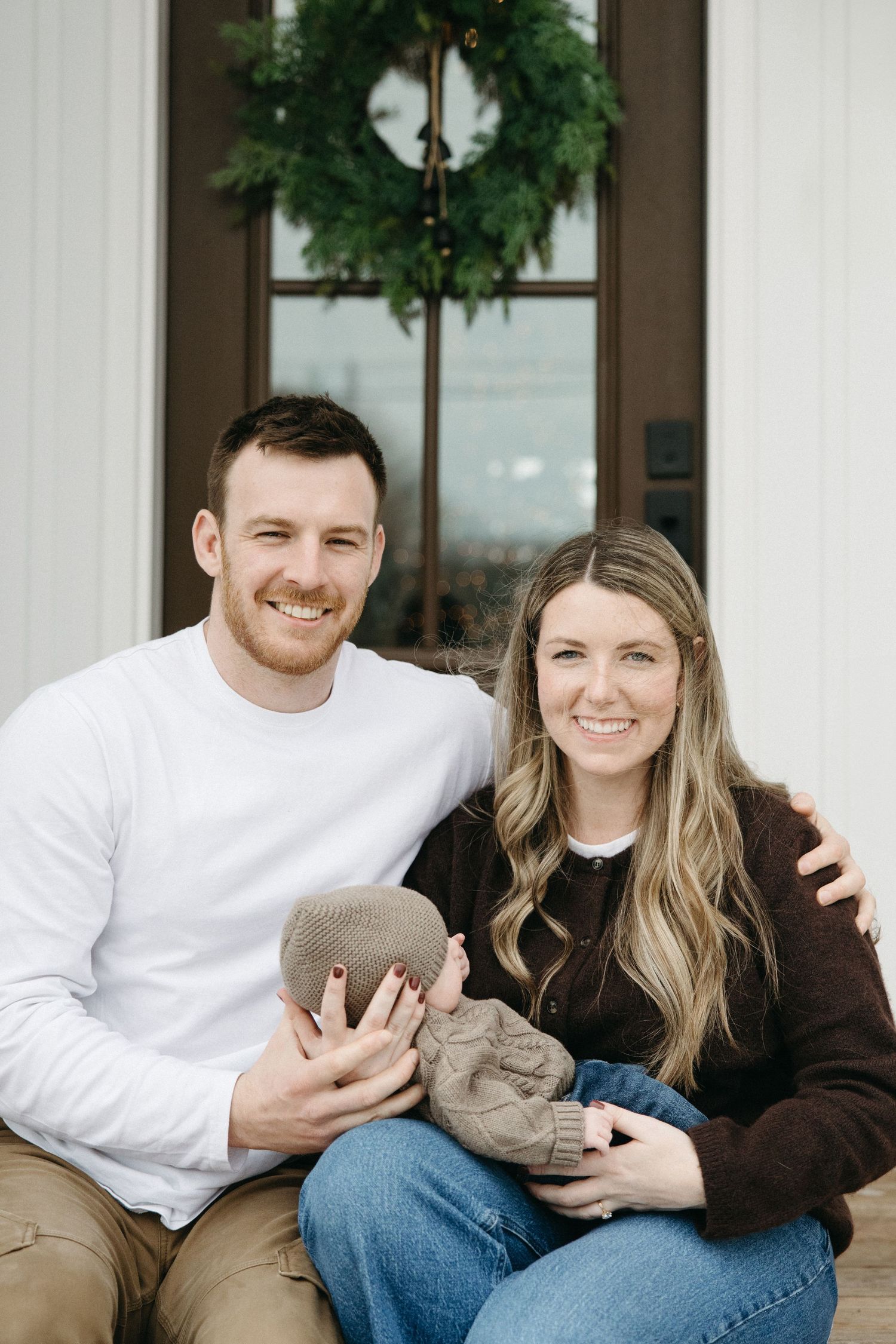 A family sits together on a white porch during a winter photo session.