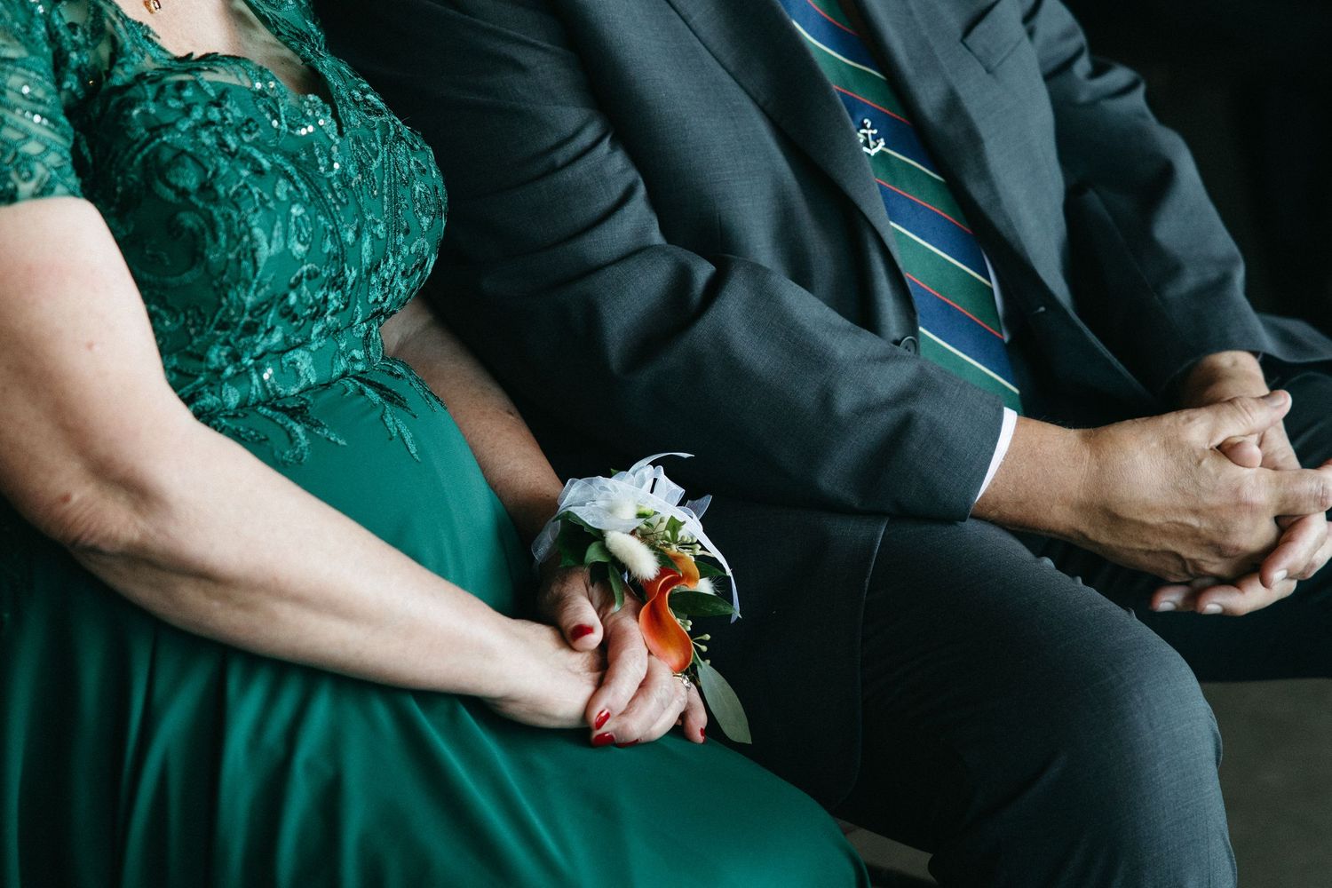 Wedding attendees in emerald green and black formal attire seated together.