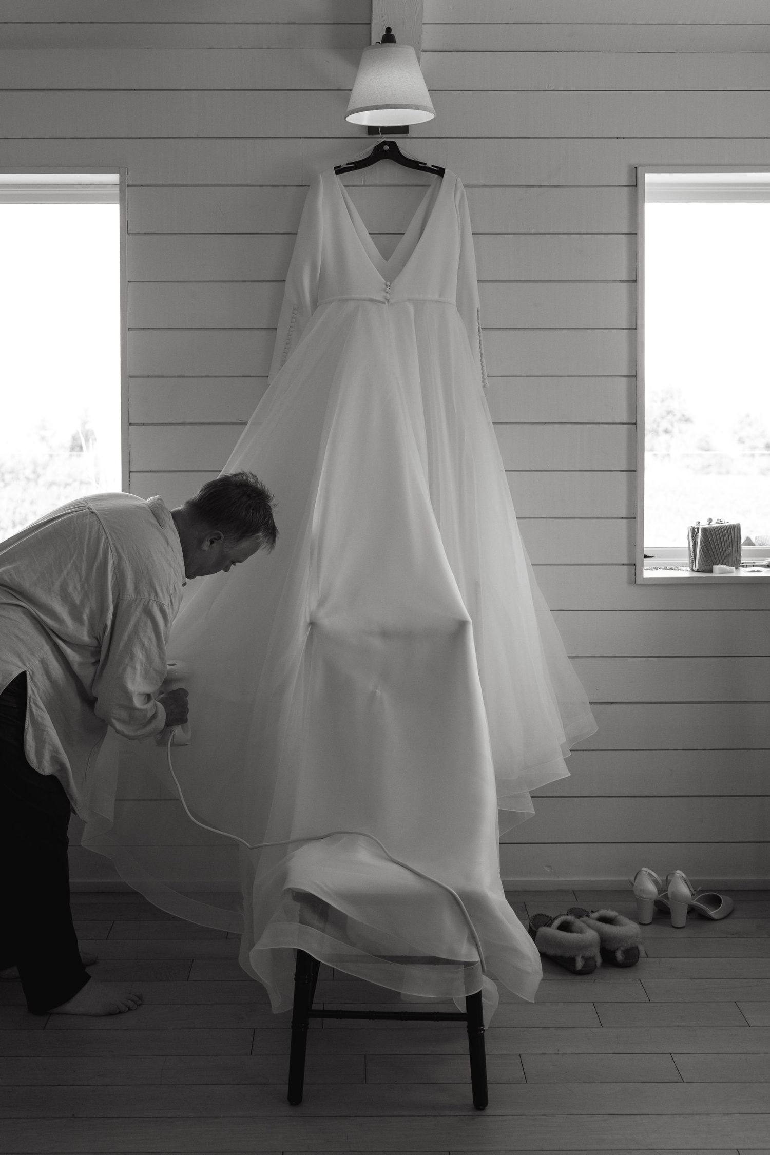 White wedding dress hangs elegantly against shiplap walls in natural light.