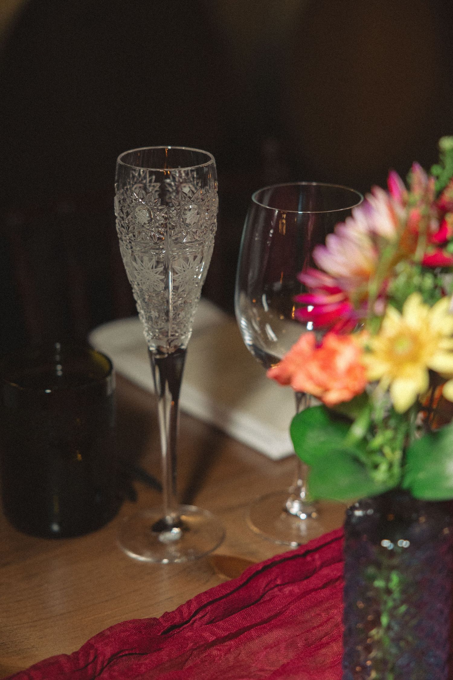 Elegant table setting with crystal wine glasses and colorful floral centerpieces.