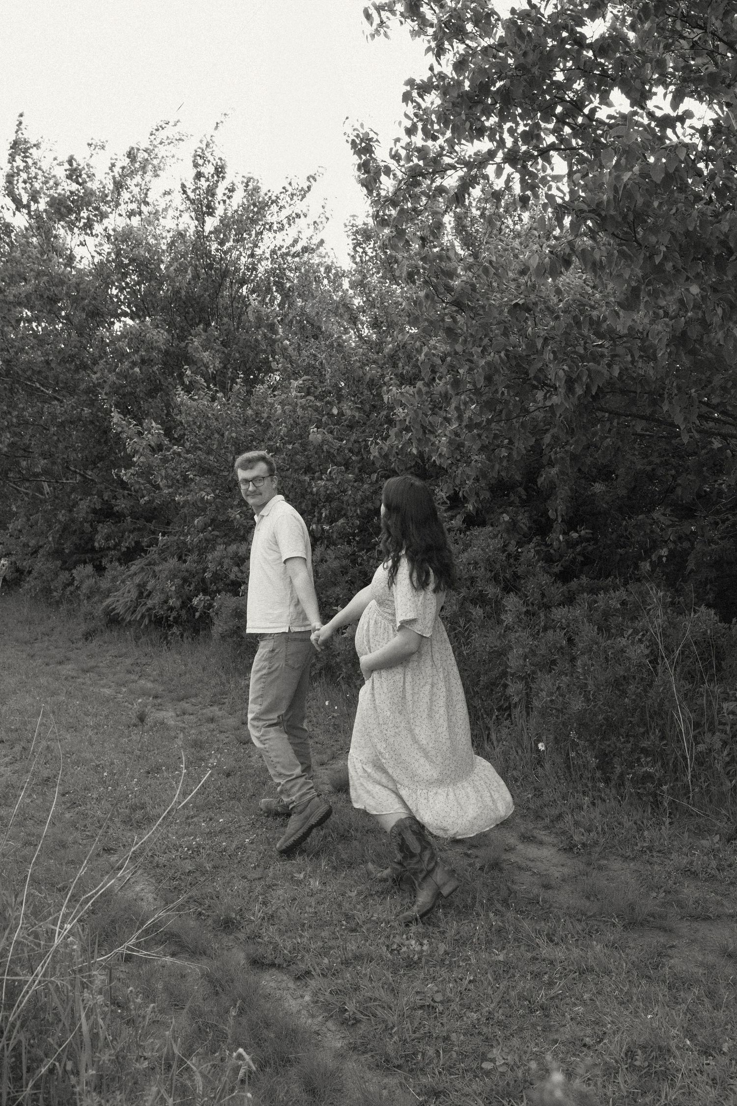Black and white photo of a couple walking up a hillside path together.