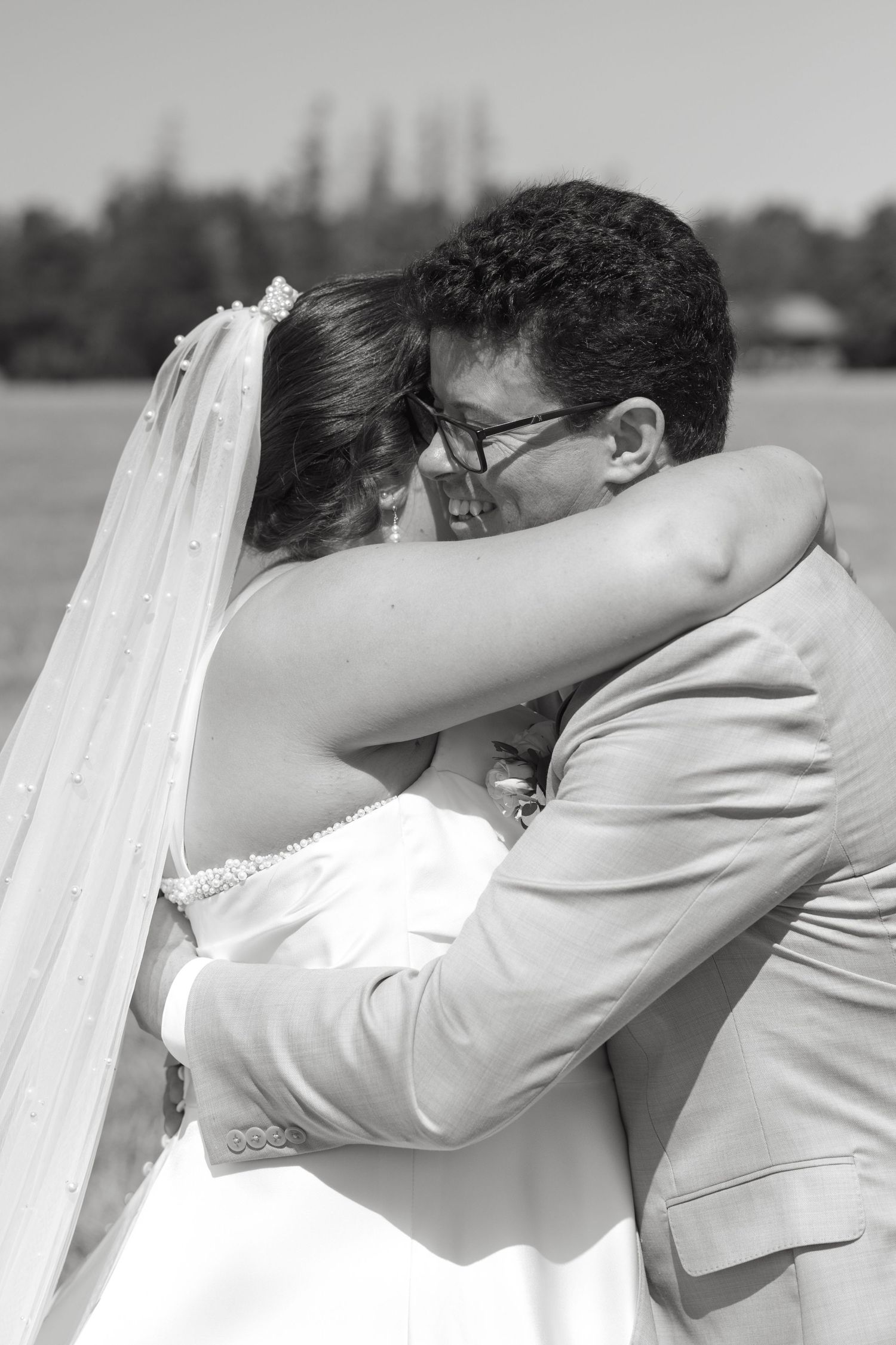 Black and white photo of bride and groom sharing a romantic embrace on their wedding day outdoors.