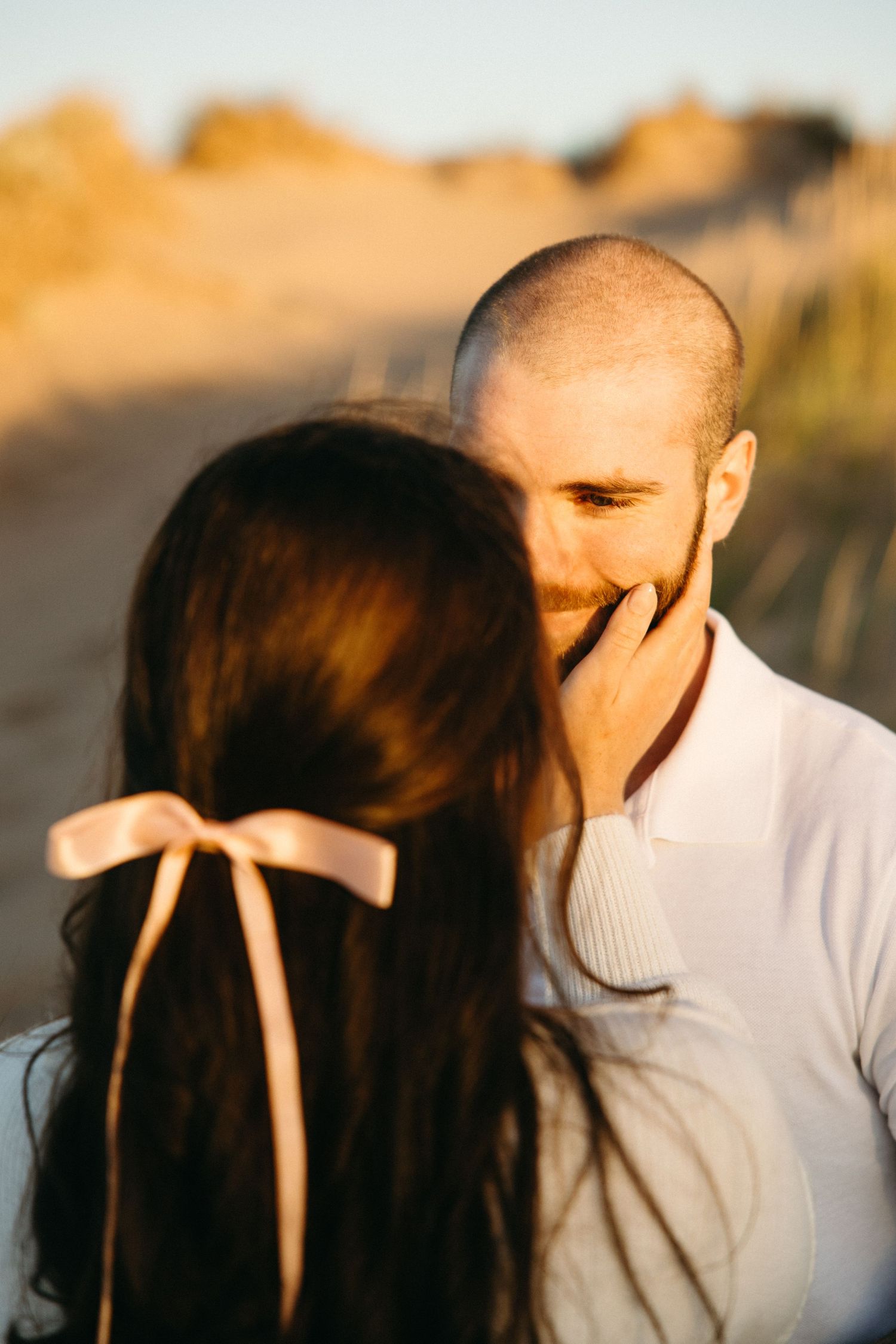 Romantic couple sharing an intimate moment at sunset on a beach with golden light.