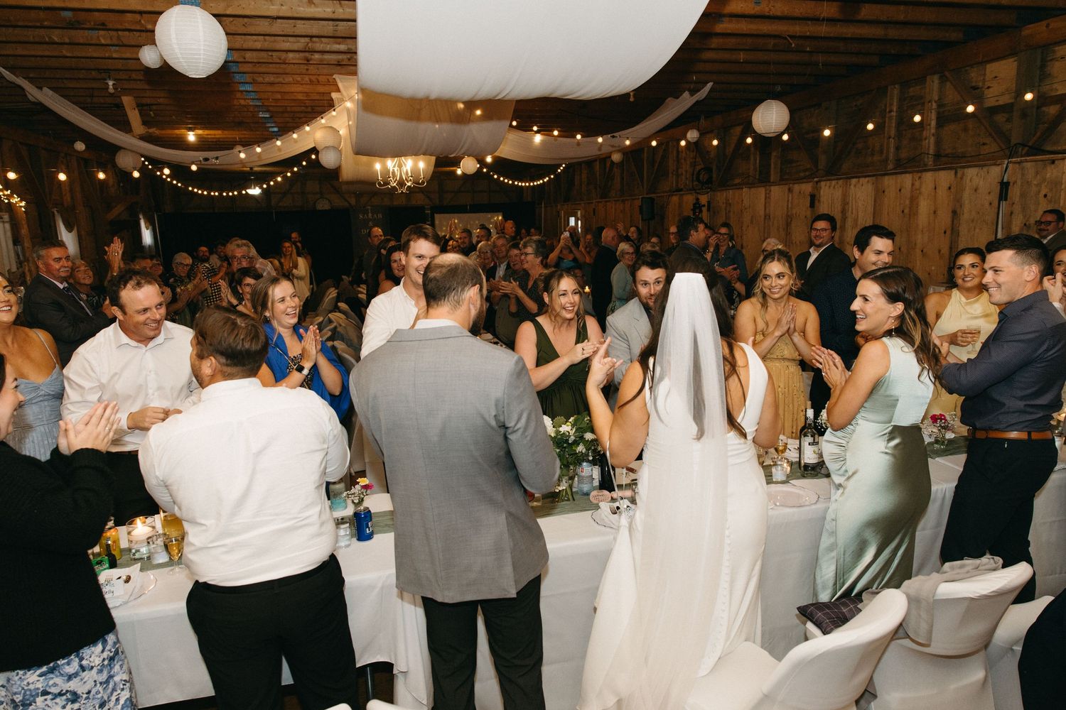 Wedding reception guests enjoying themselves on the dance floor under decorative string lights.
