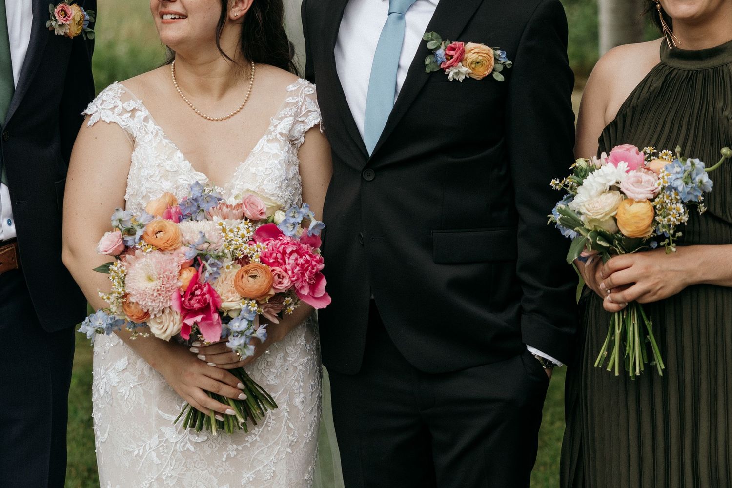 Wedding party members holding colorful bouquets while wearing formal attire.