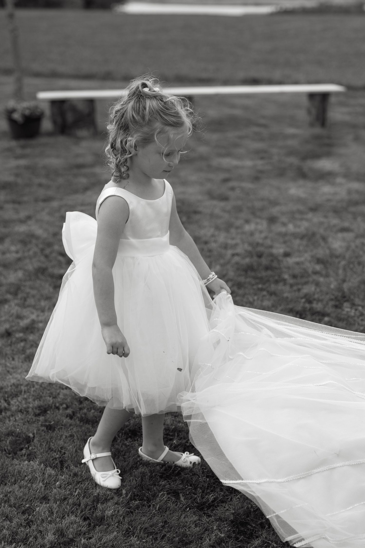 Black and white photos of flowing white dresses moving in the wind on a grassy field.