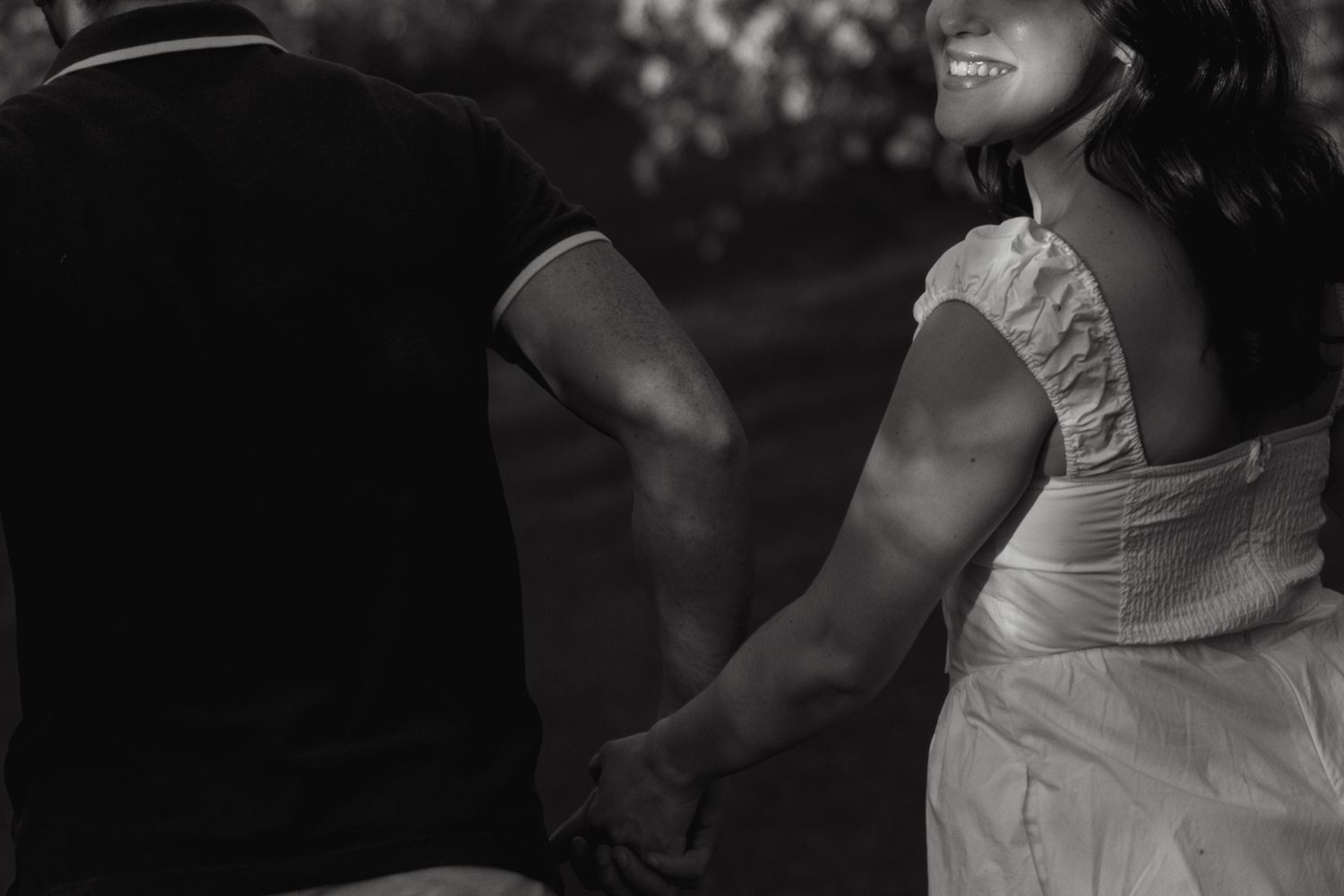 Black and white photo of couple holding hands in wedding attire.