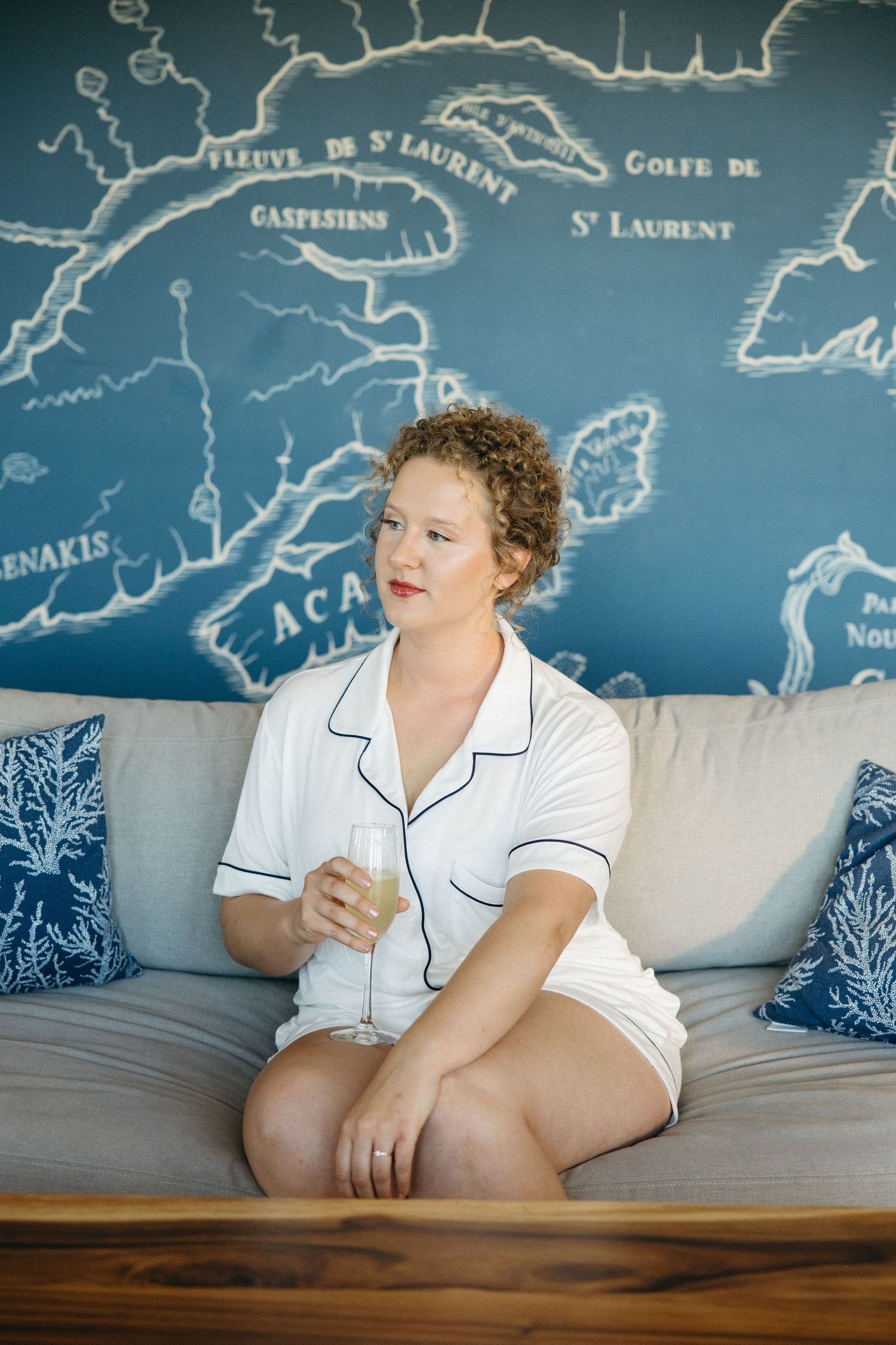 Person in white pajamas sitting on couch with vintage map wall art behind them.