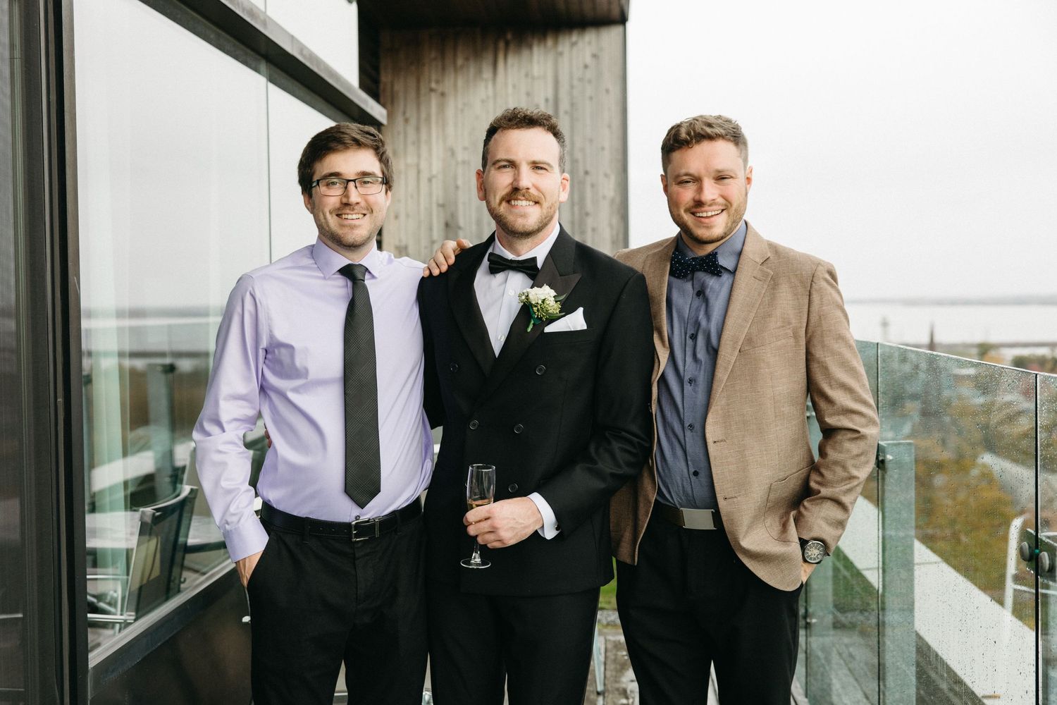 A group in business attire stands together on an outdoor terrace with city views.