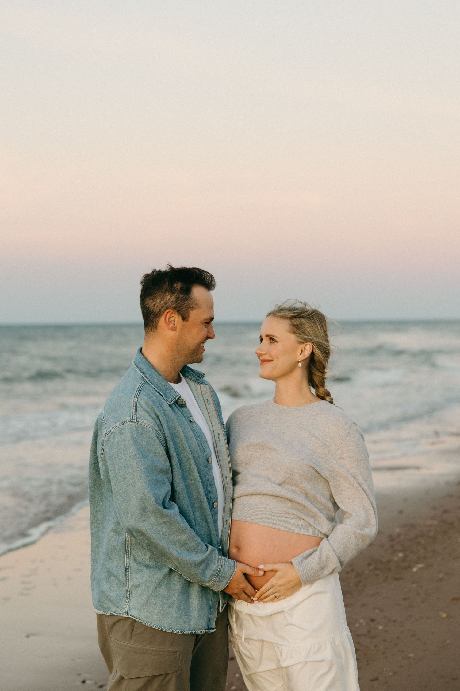 A couple shares an intimate moment on a beach at dusk.