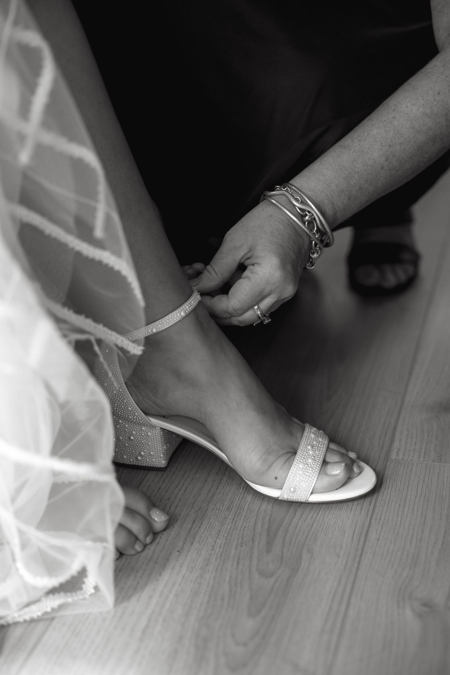 Close-up shots of white bridal shoes being put on feet against a dark background.