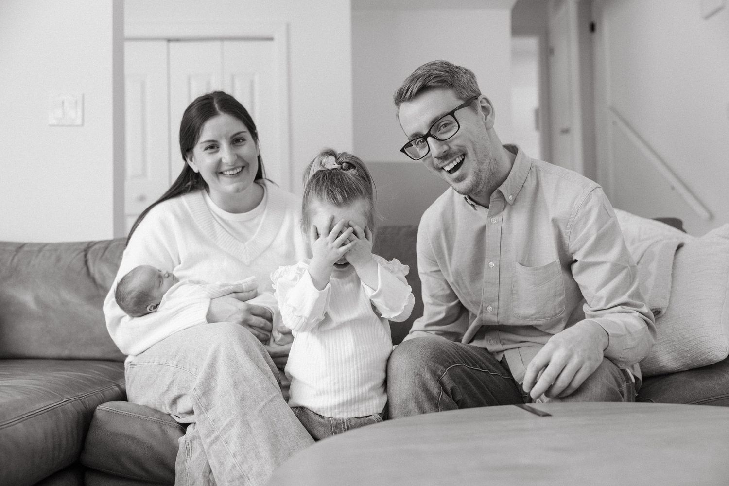 Natural lifestyle photos of family bonding with newborn in white modern home setting.