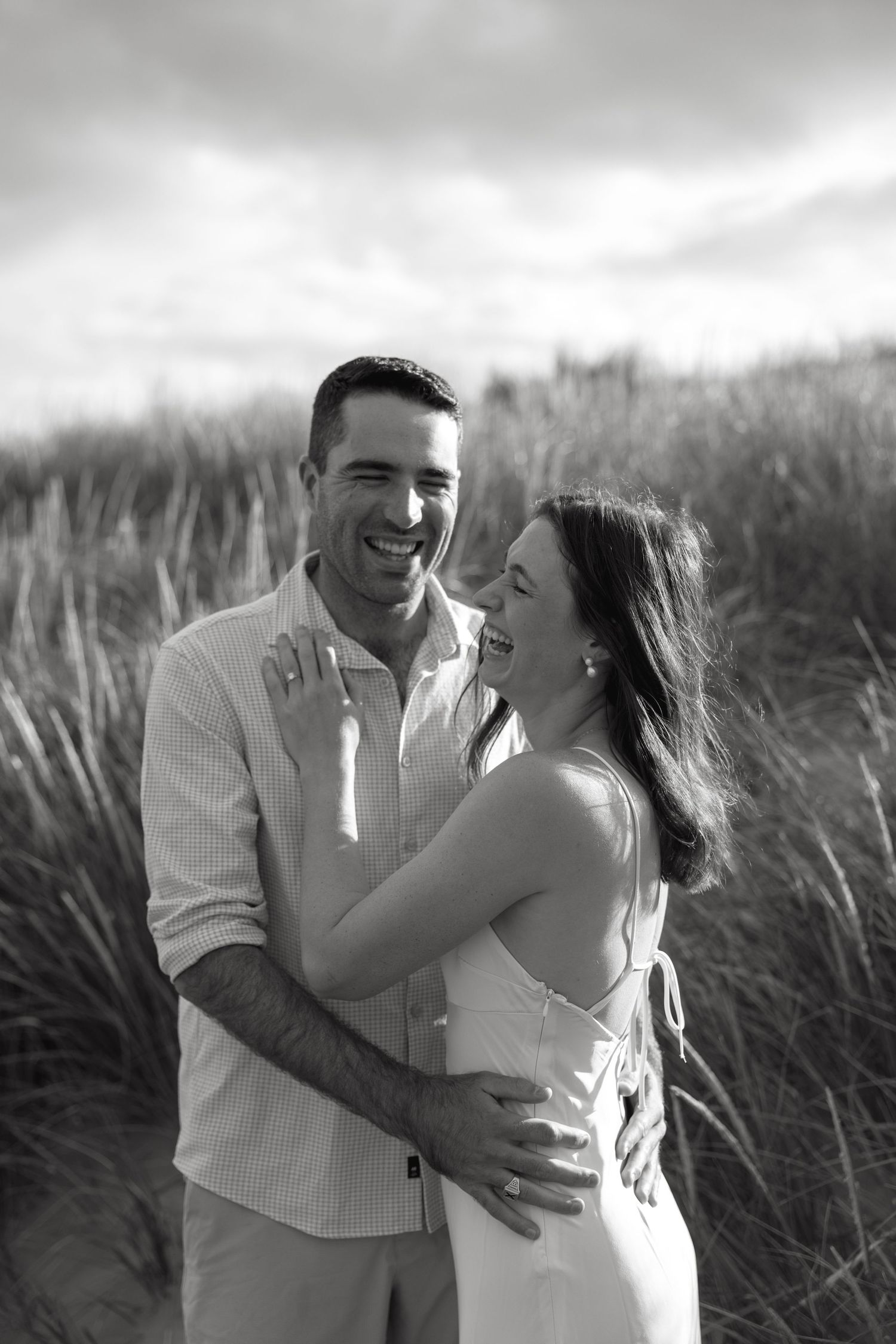 A romantic black and white photo series of a couple embracing in tall grass.