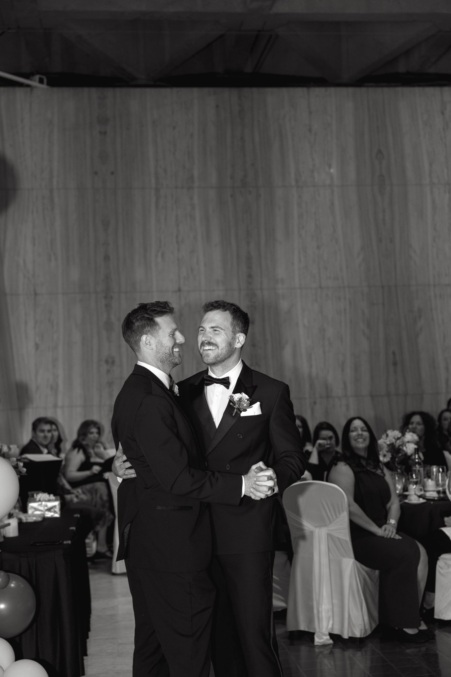 Black and white photo of two people sharing a joyful dance at a formal event.