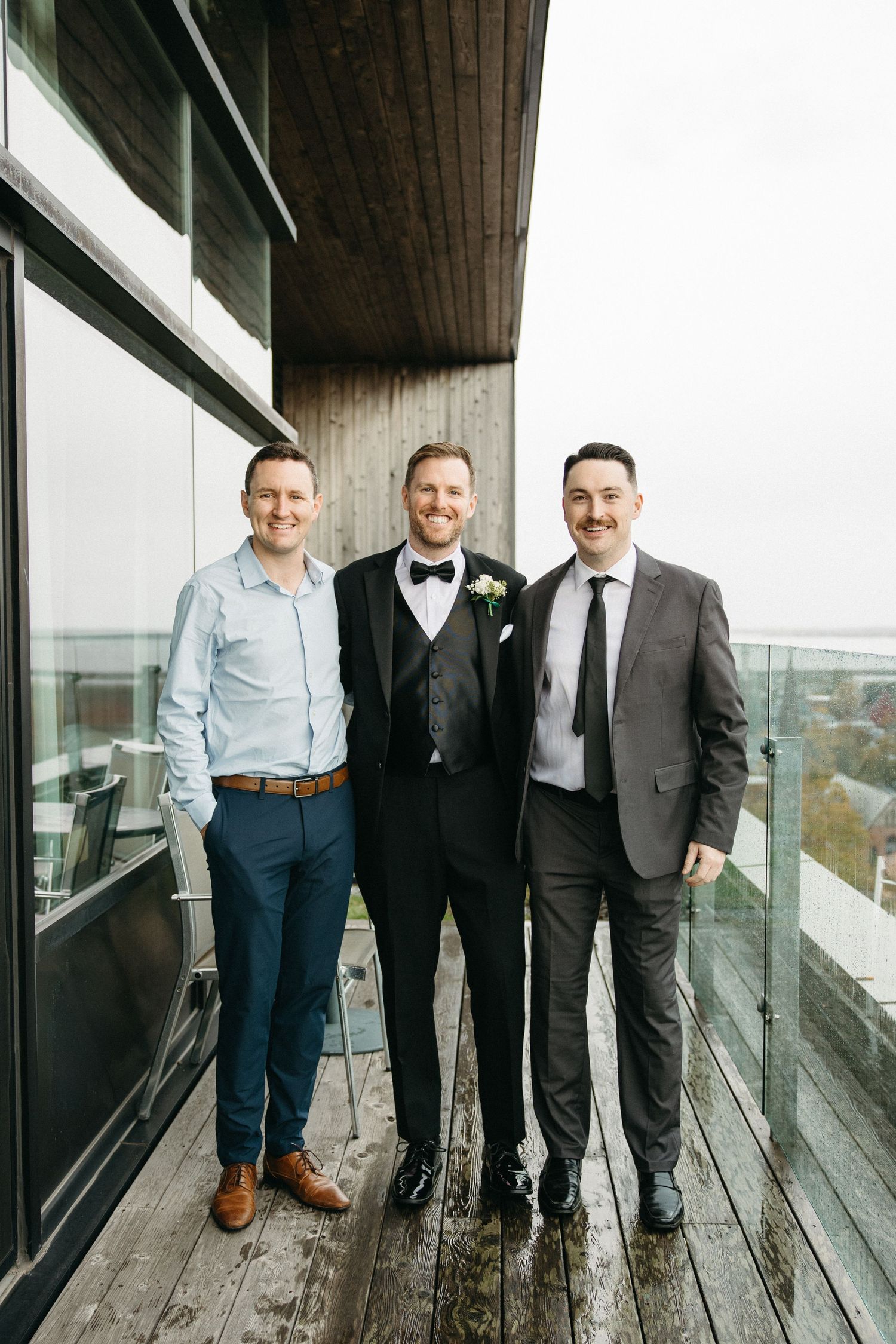 Three people in business attire stand together on a modern outdoor deck.