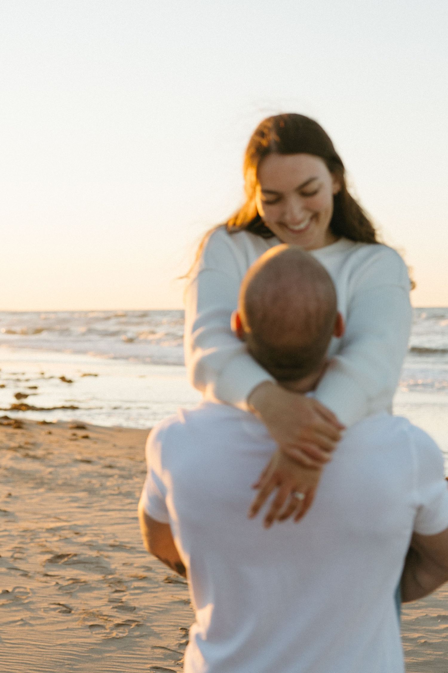 Intimate moment shared between couple on sandy beach at sunset.